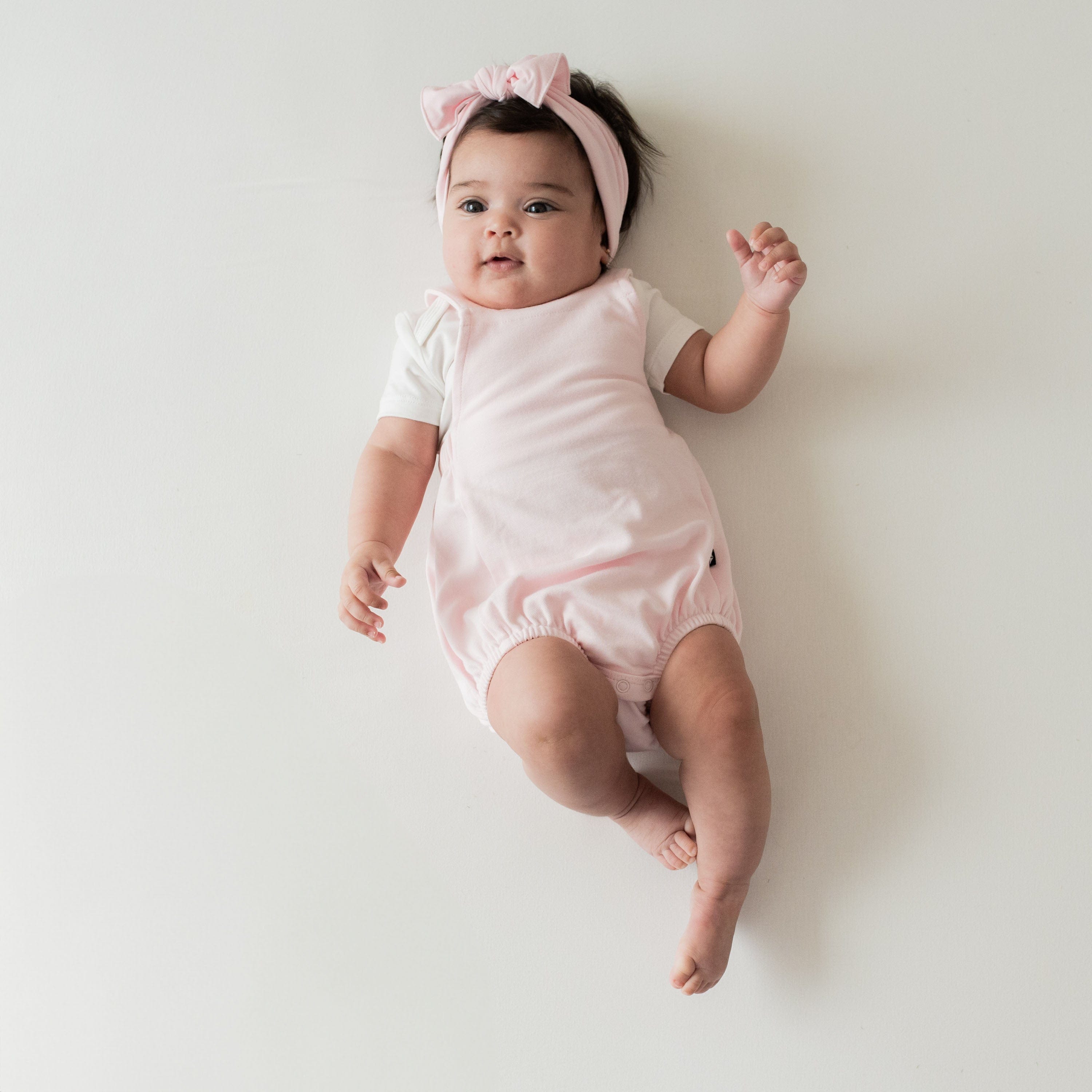Infant wearing Kyte Baby Bamboo Jersey Bubble Overall with Crossover Straps in Sakura pink