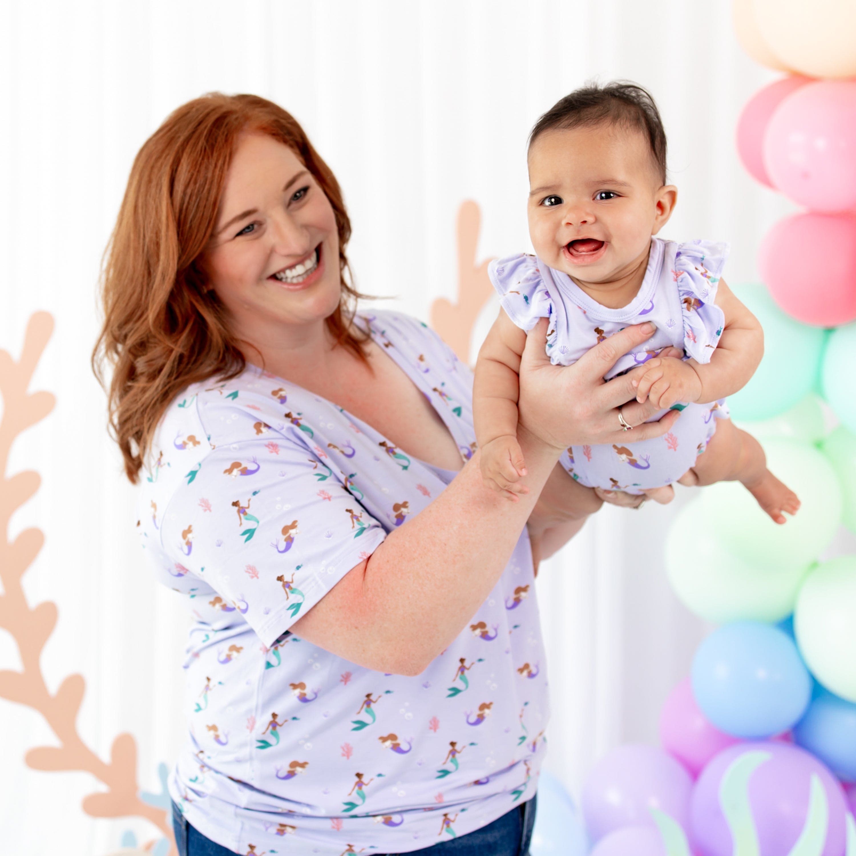 Mom holding infant wearing Kyte Baby Bubble Romper in Mermaid