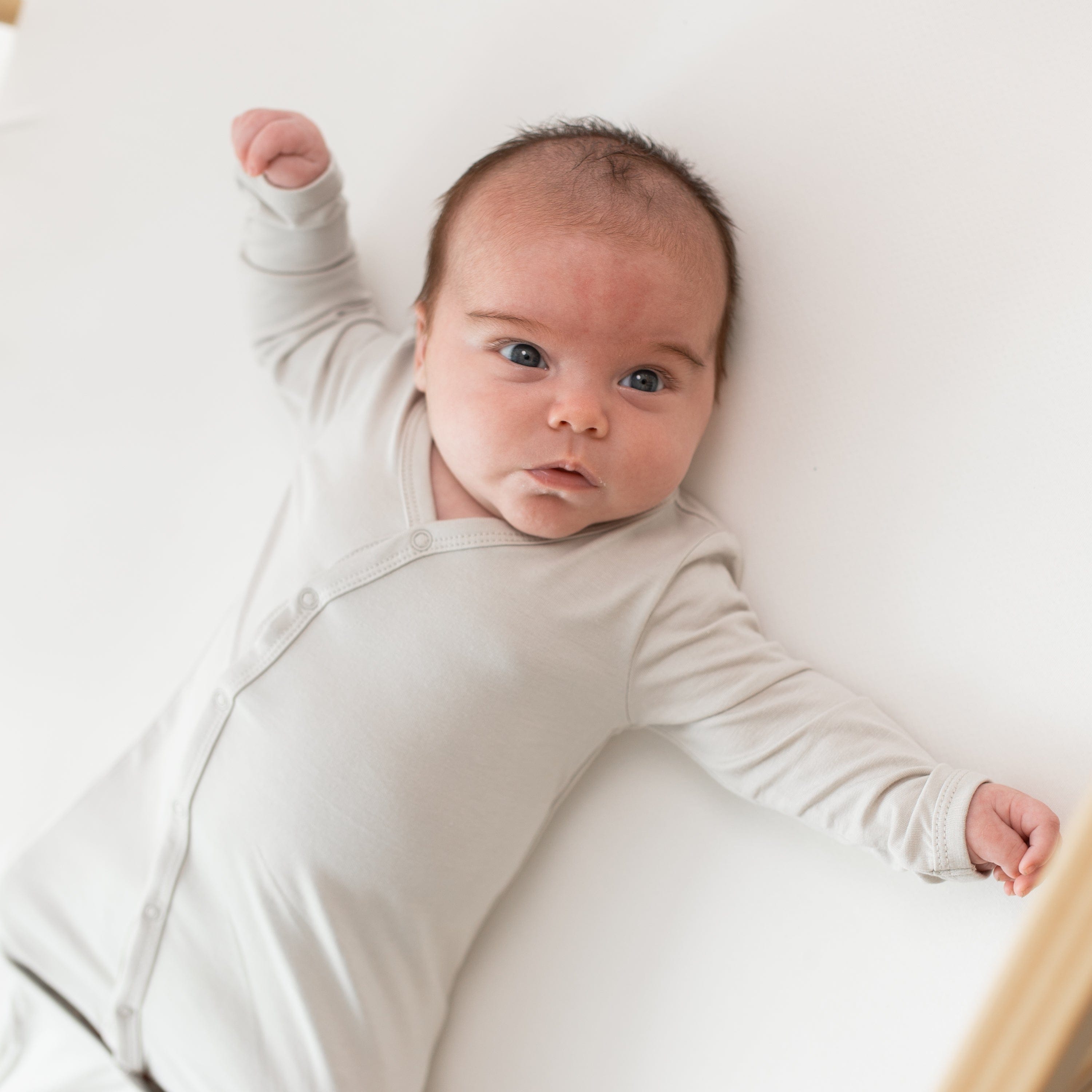Close up of newborn wearing the Kyte Baby Bundler in Oat, showcasing the snaps
