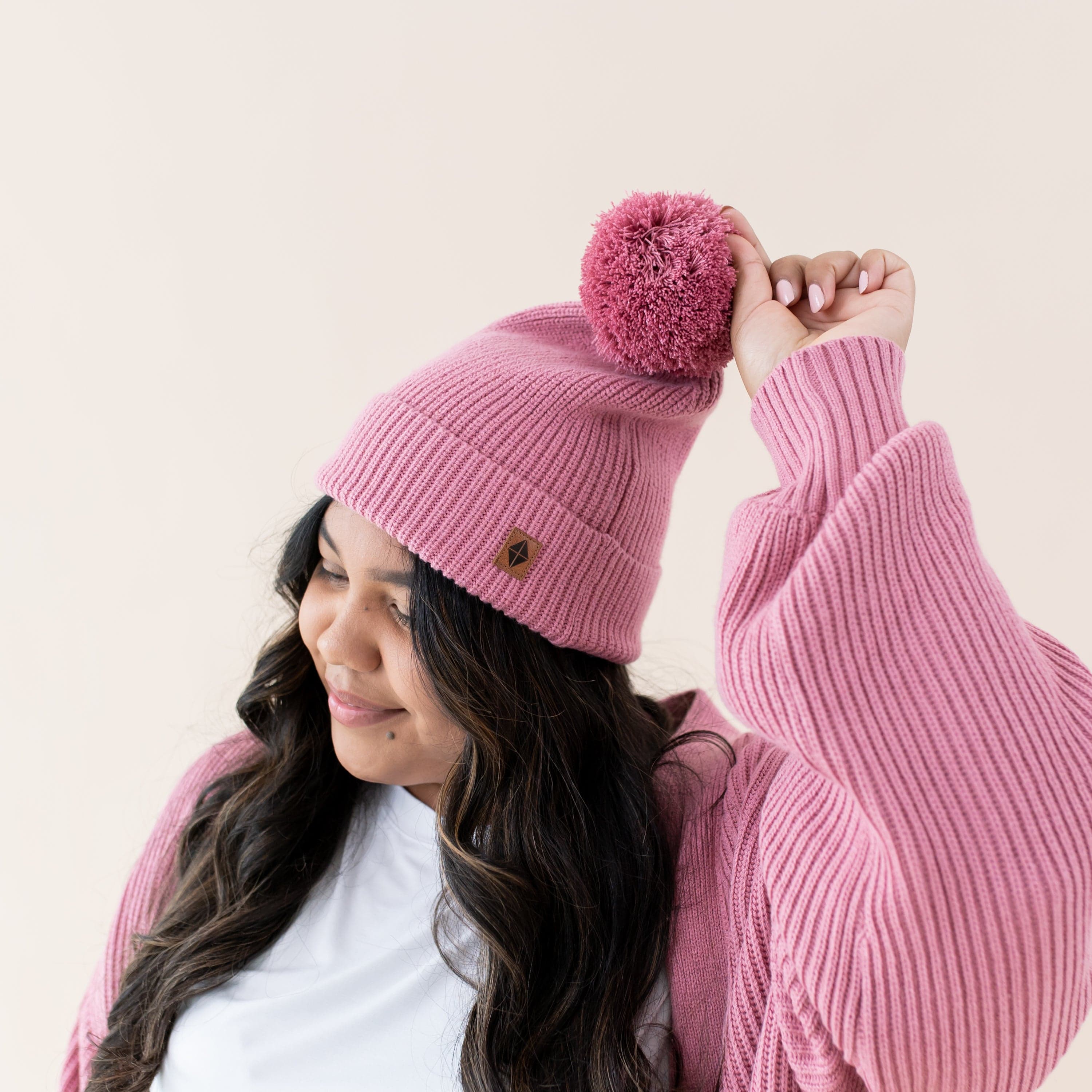Woman wearing Kyte Baby Chunky Knit Adult Pom Beanie in Apple Blossom
