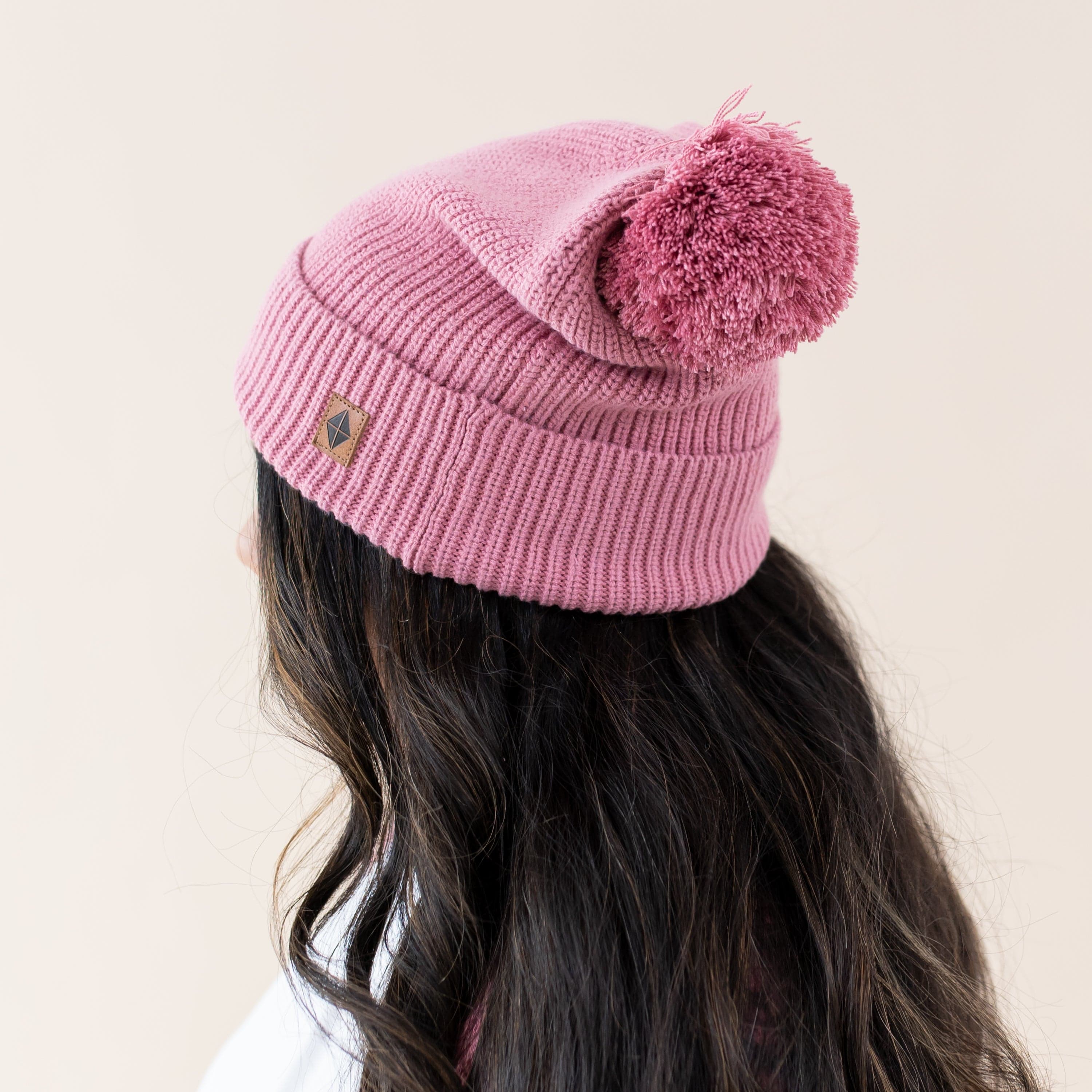 Woman wearing Kyte Baby Chunky Knit Beanie with Pom Detail in Apple Blossom pink