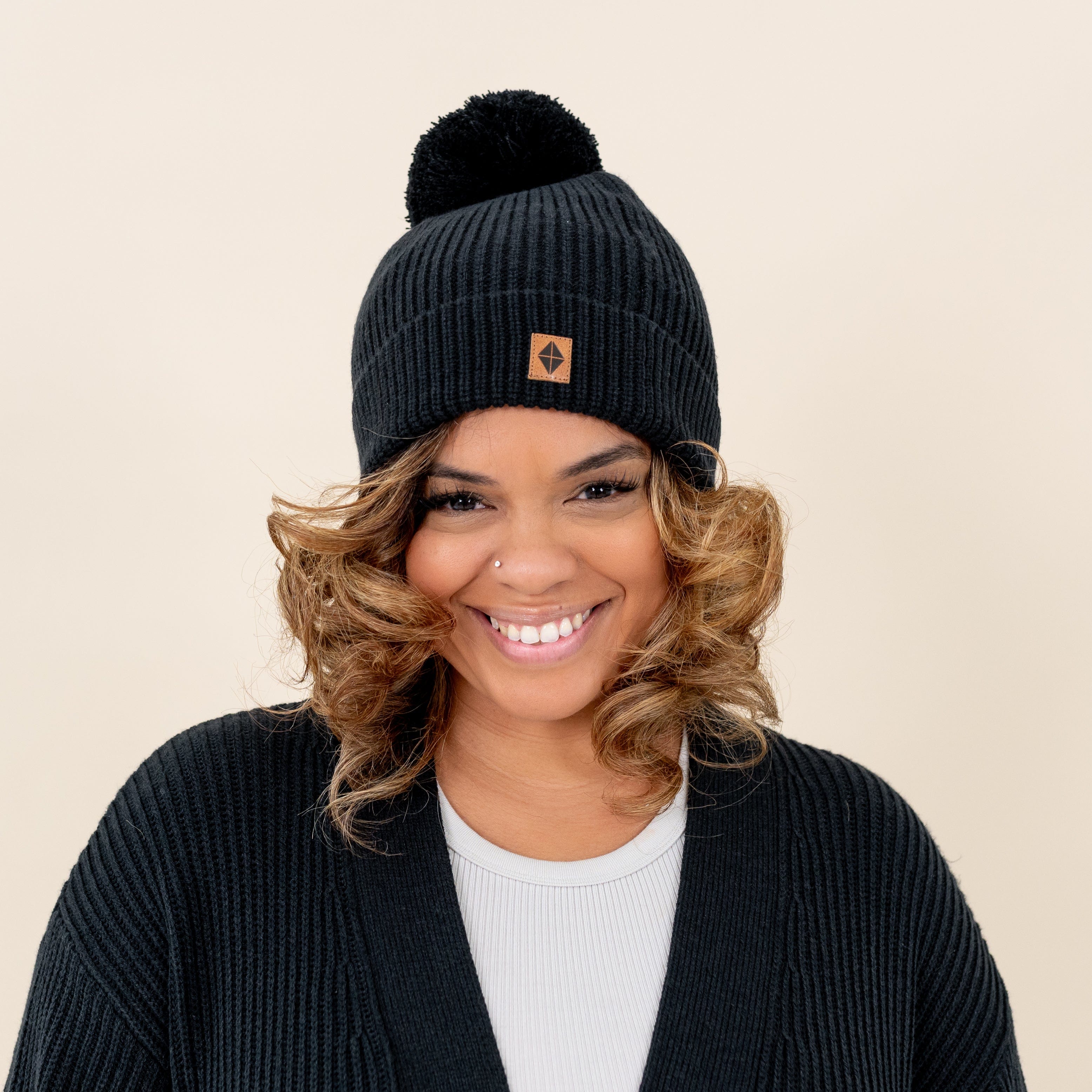 Woman wearing Kyte Baby Chunky Knit Adult Pom Beanie in Midnight