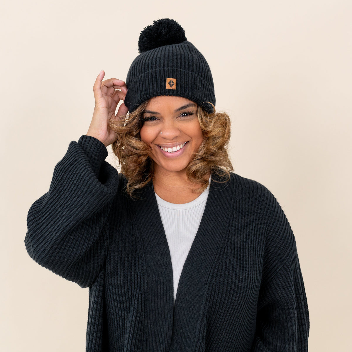 Woman wearing Kyte Baby Chunky Knit Beanie with Pom Detail in Midnight black