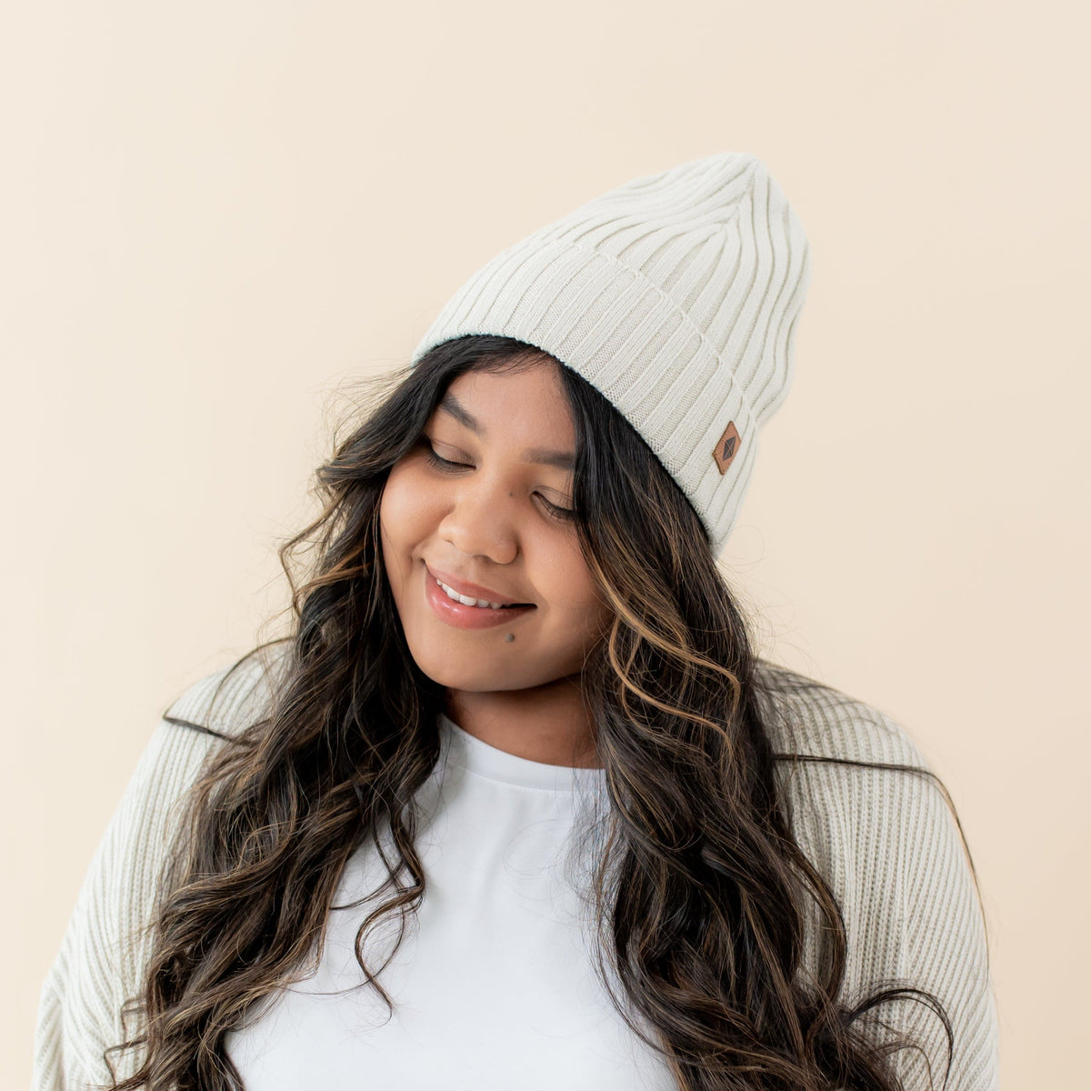 Woman wearing Kyte Baby Chunky Knit Adult Ribbed Beanie in Oat
