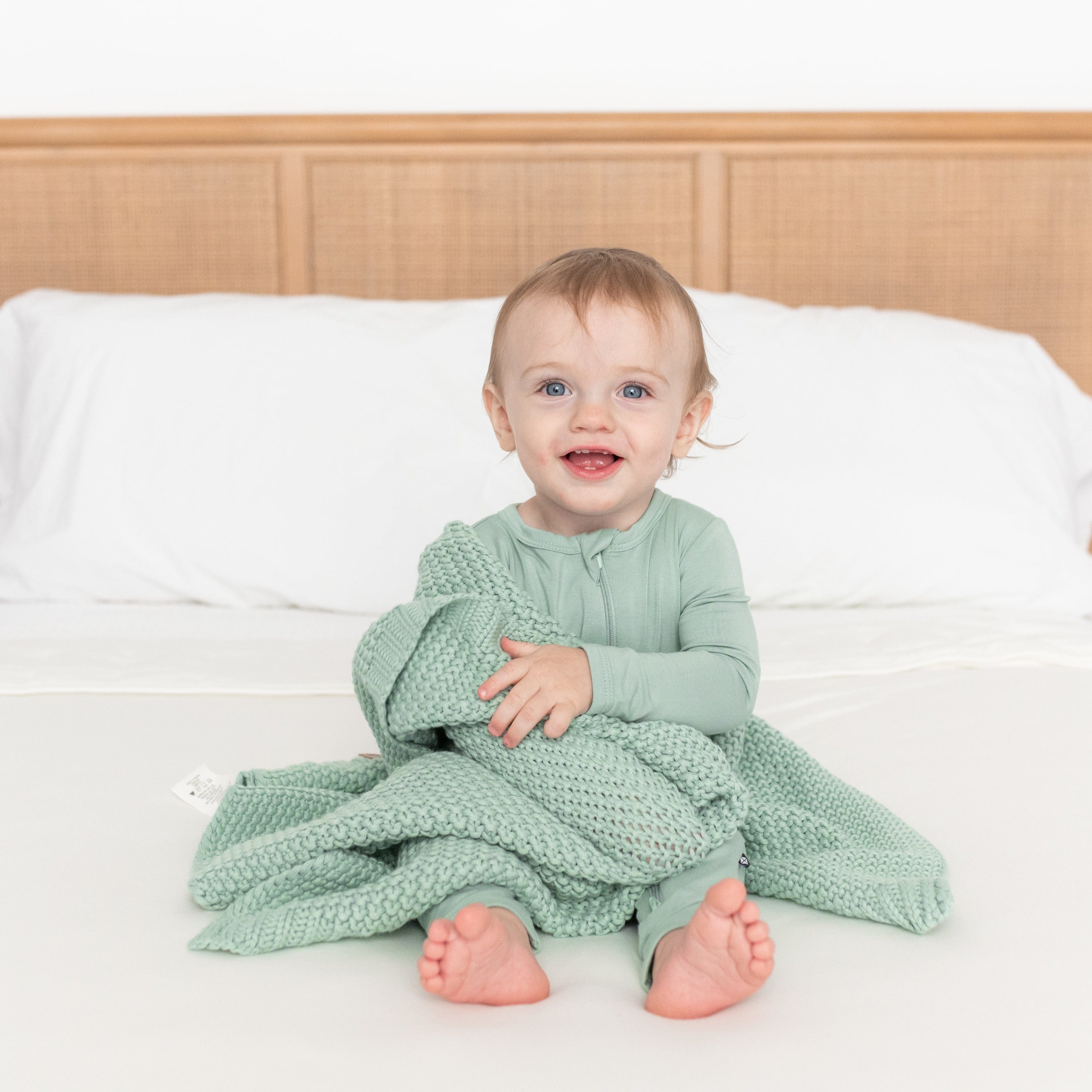 Infant wrapped in Kyte Baby Chunky Knit Baby Blanket in Sage Green