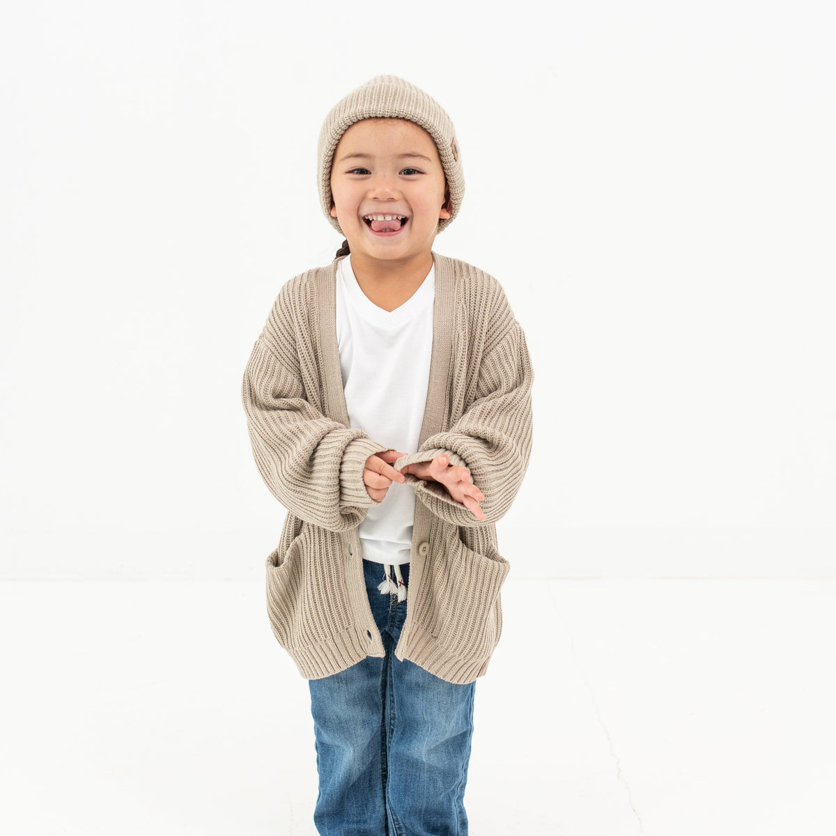 Child wearing Kyte Baby Chunky Knit Oversized Cardigan with front pockets in Almond