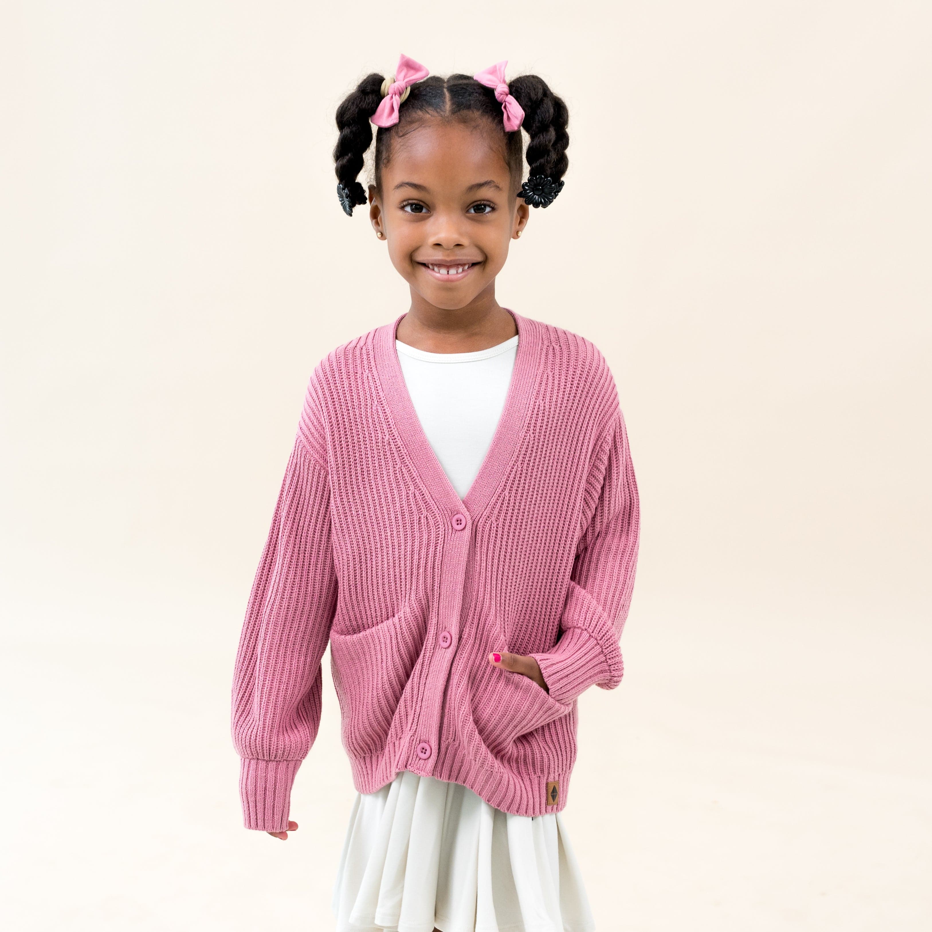 Girl wearing Kyte Baby Chunky Knit Oversized Cardigan in Apple Blossom