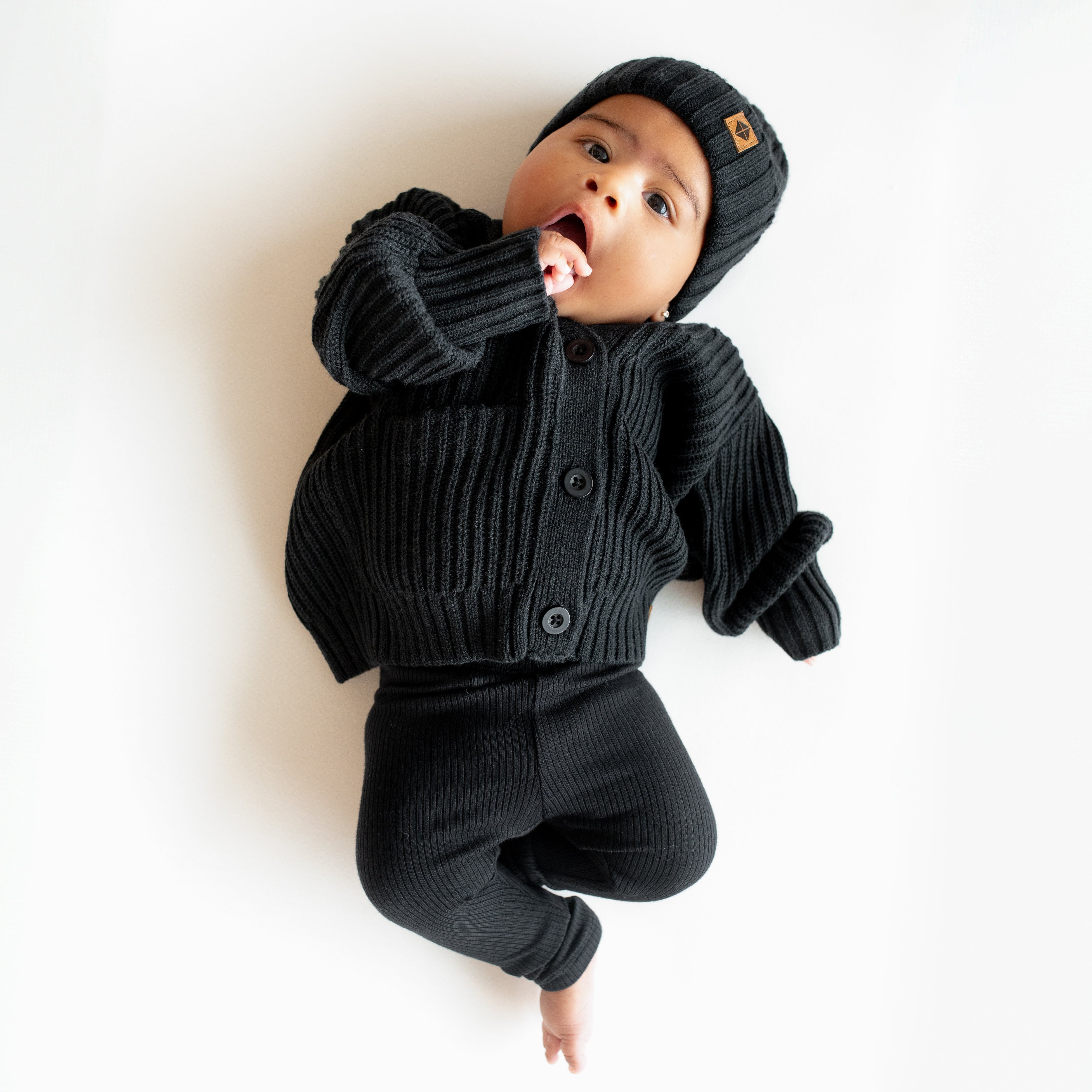 Infant wearing Kyte Baby Chunky Knit Oversized Cardigan in Midnight black