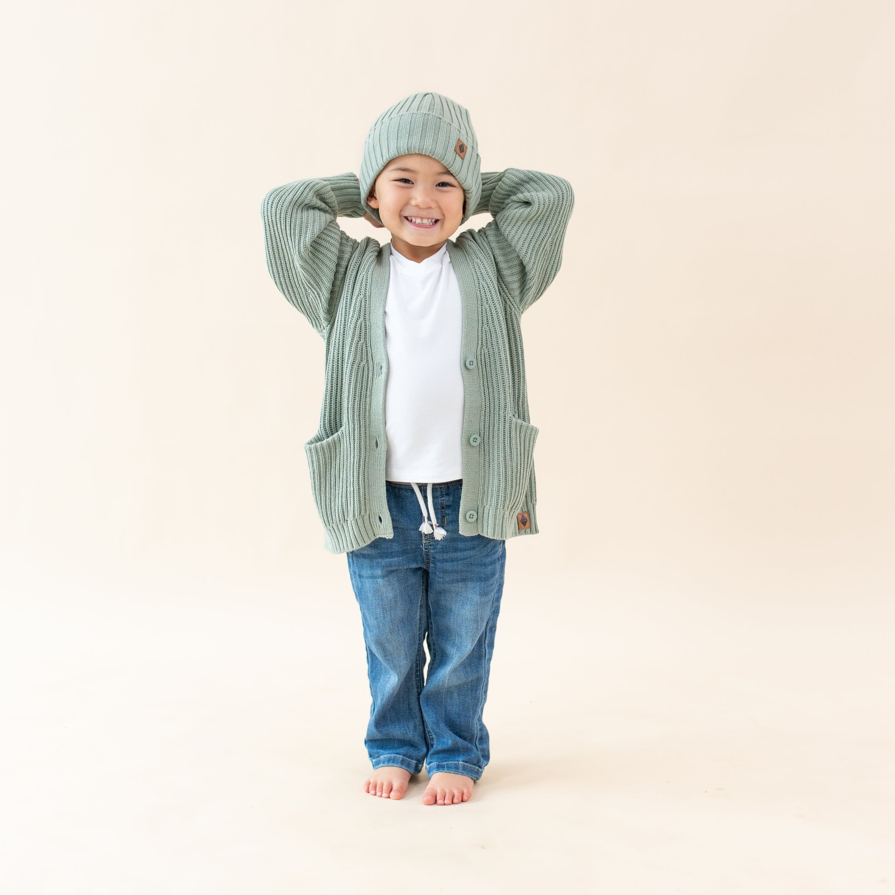 Child wearing Kyte Baby Chunky Knit Oversized Cardigan in Thyme