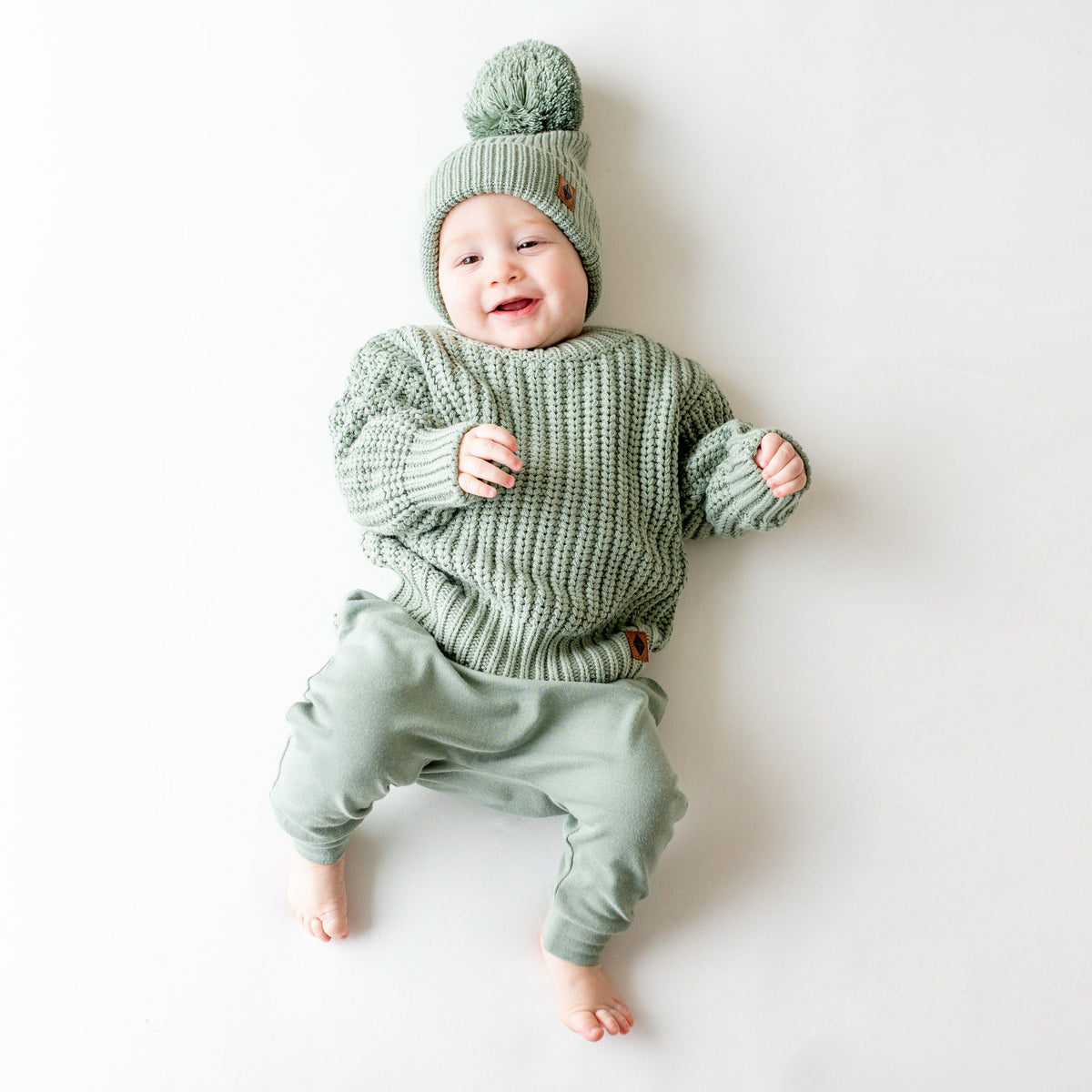 Infant wearing Kyte Baby Chunky Knit Pom Beanie in Thyme