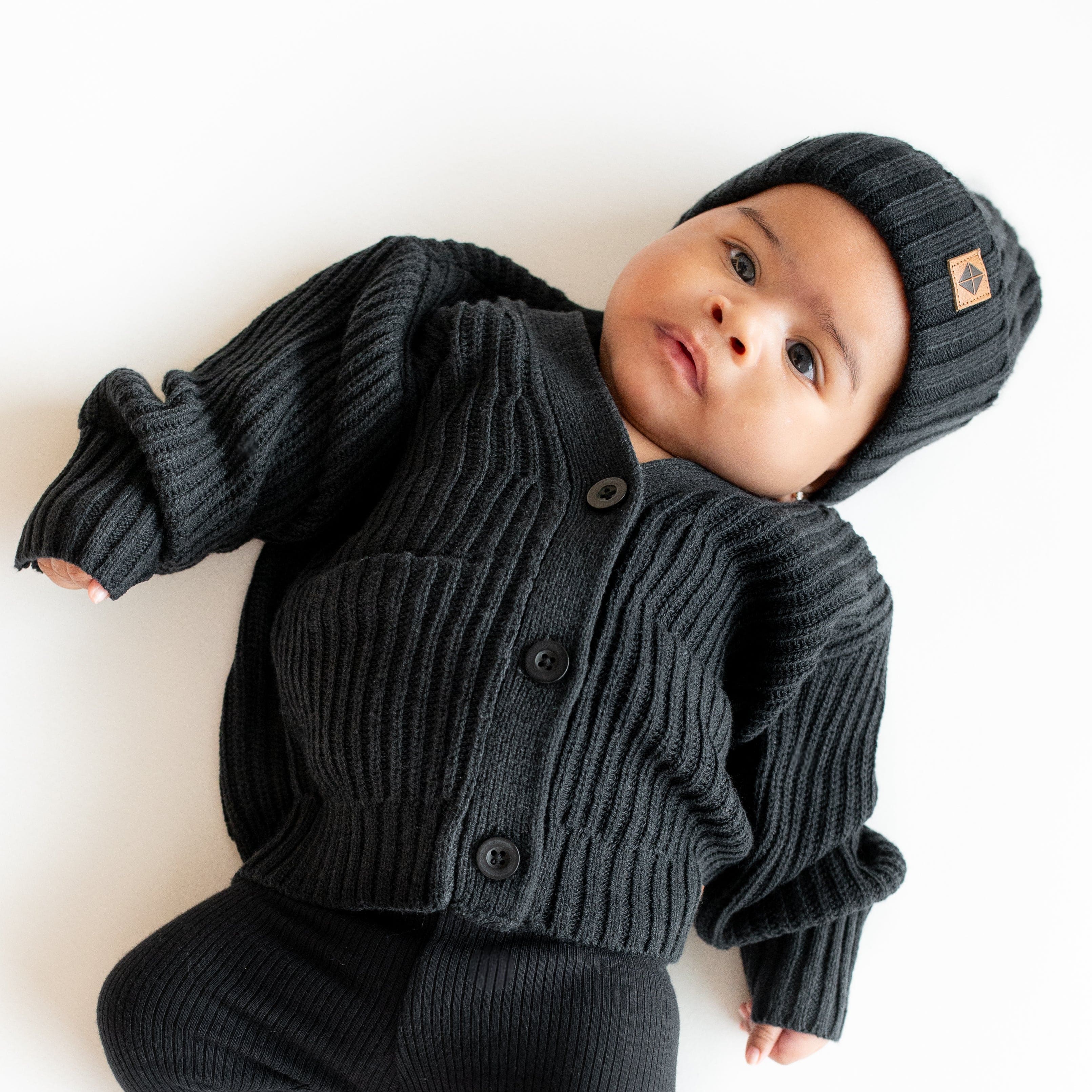 Infant wearing Kyte Baby Chunky Knit Ribbed Beanie in Midnight black