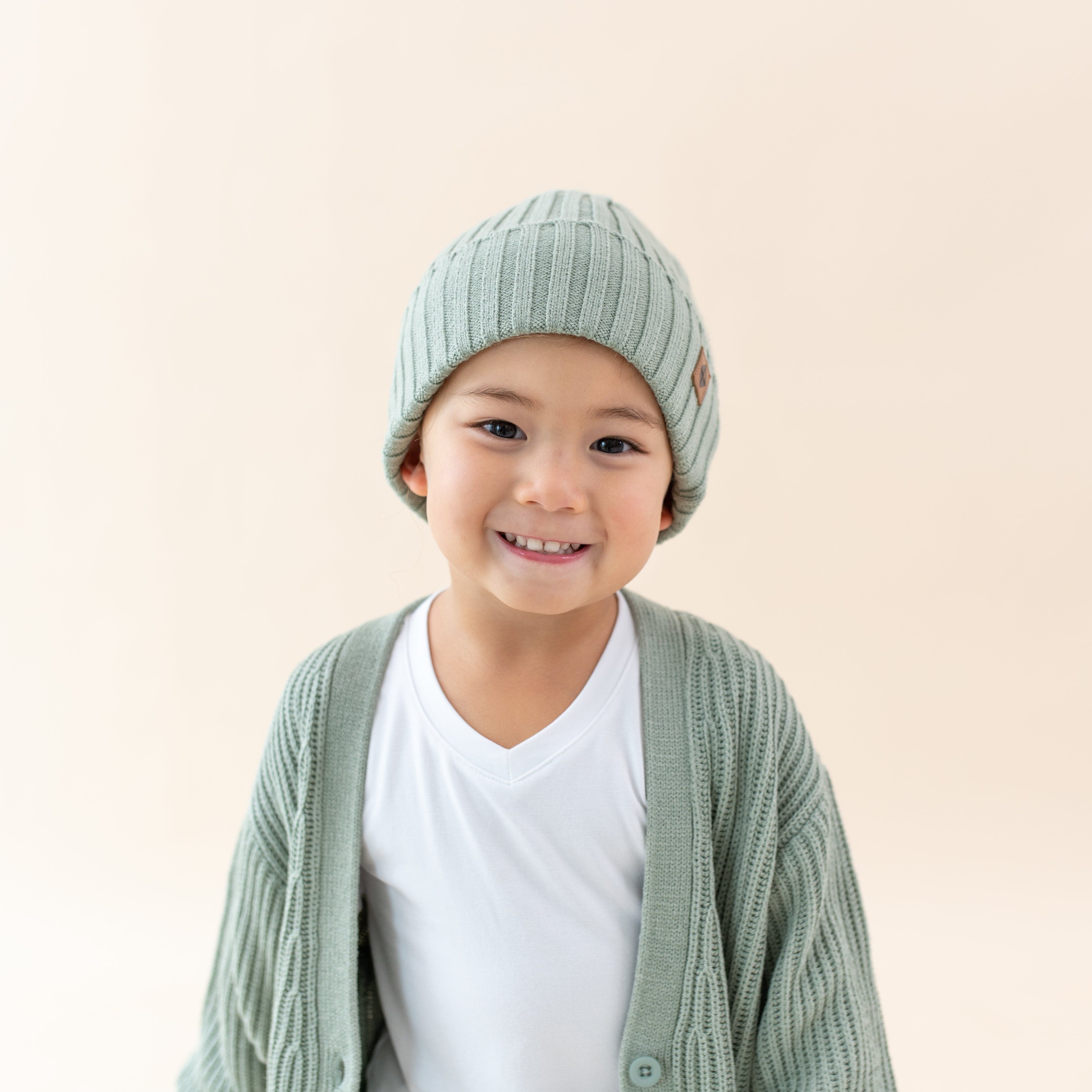 Child wearing soft and stretch Kyte Baby Chunky Knit Ribbed Beanie in Thyme green