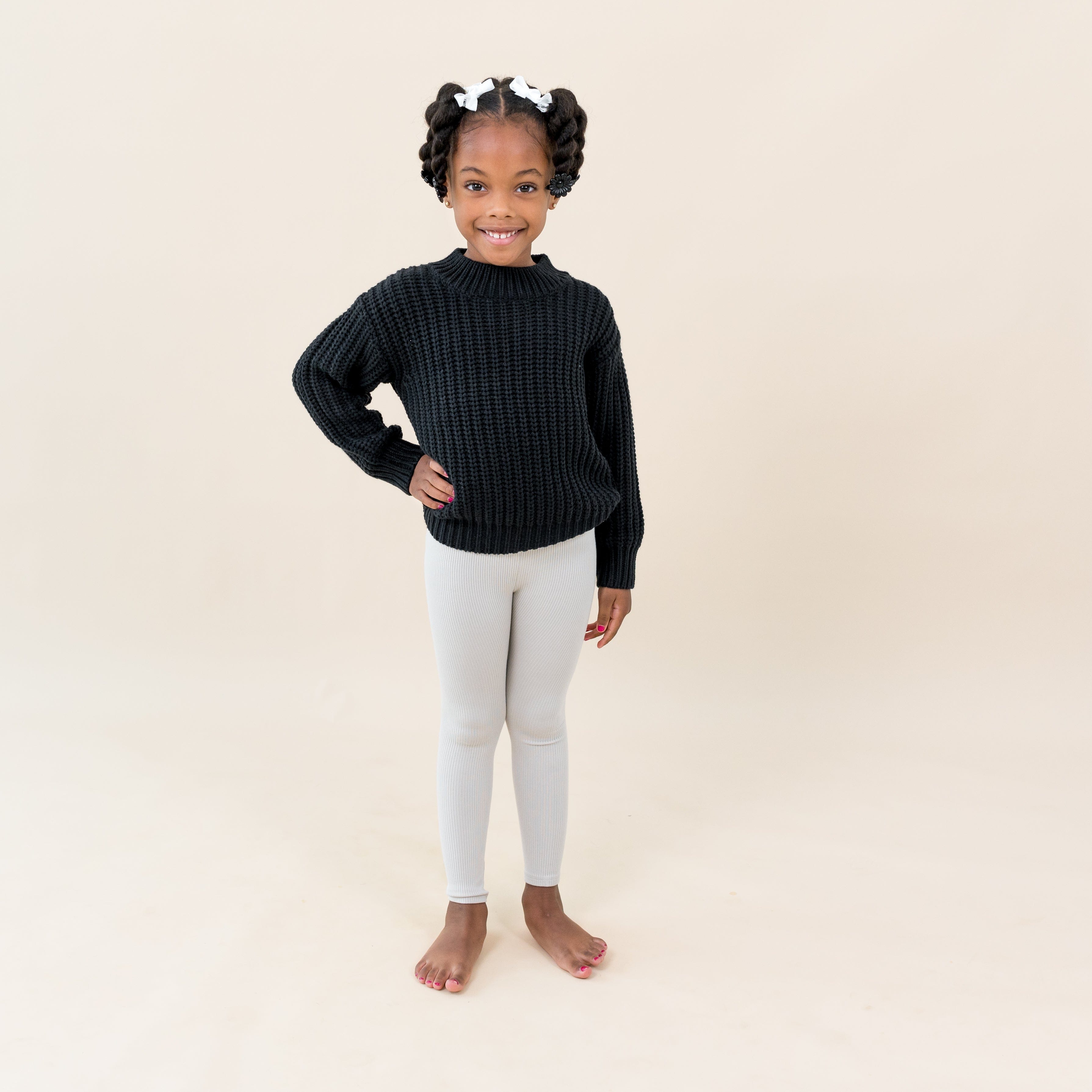Child wearing Kyte Baby Ribbed Leggings in Oat with Chunky Knit Sweater in Midnight