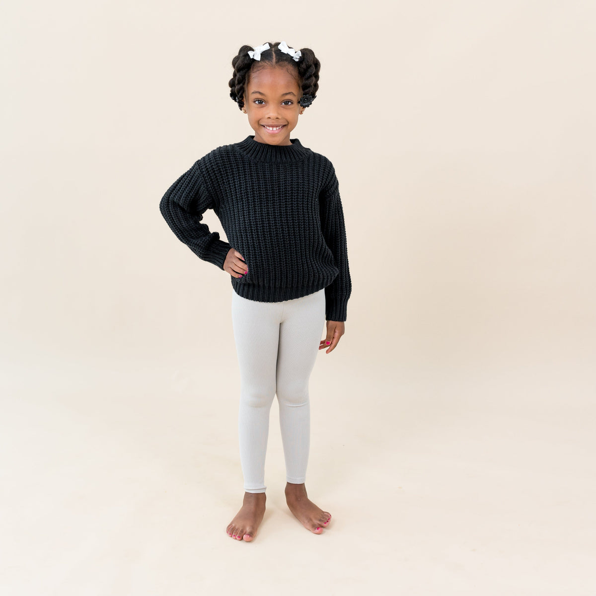 Child wearing Kyte Baby Ribbed Leggings in Oat with Chunky Knit Sweater in Midnight