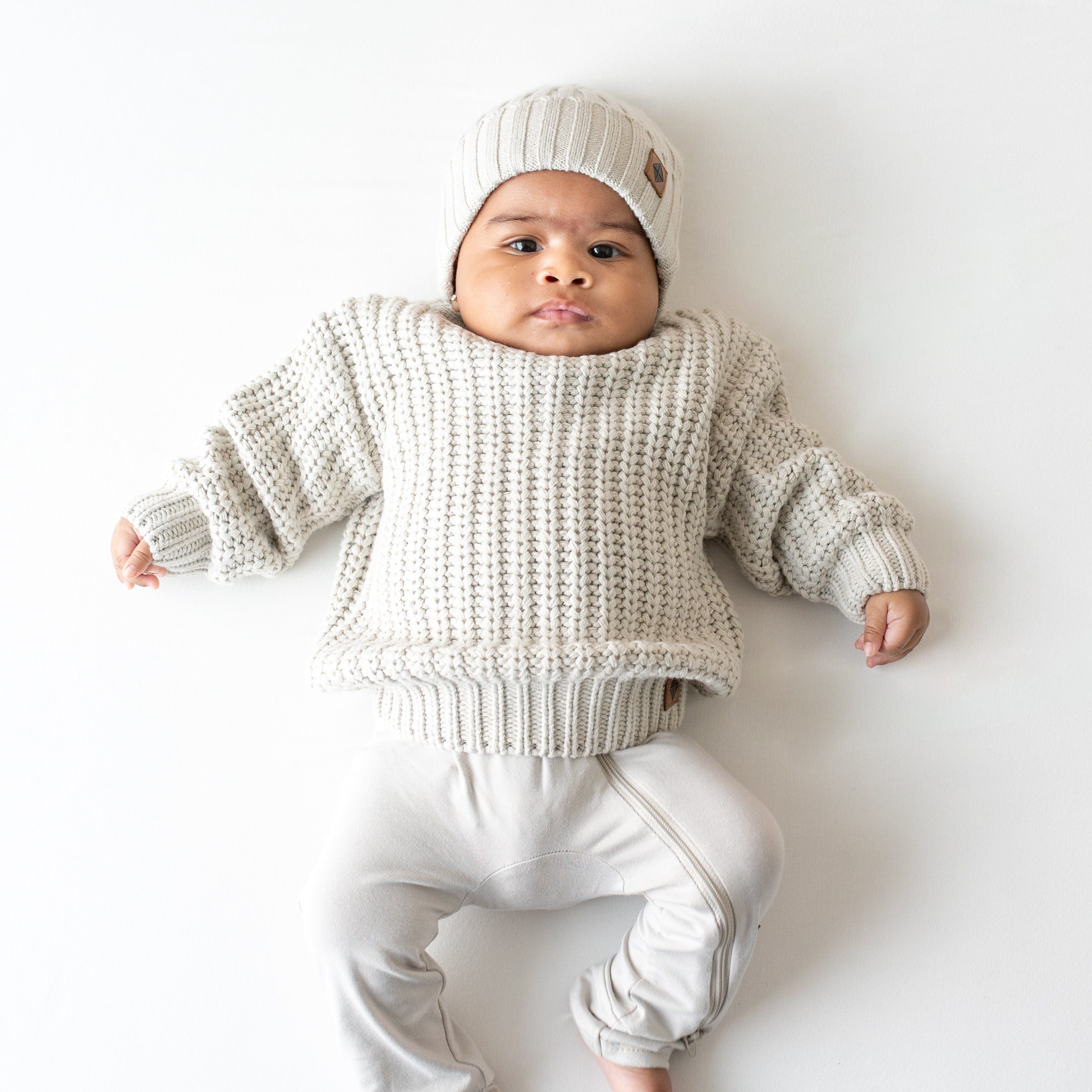 Infant wearing soft and stretchy Kyte Baby Chunky Knit Sweater in Oat neutral
