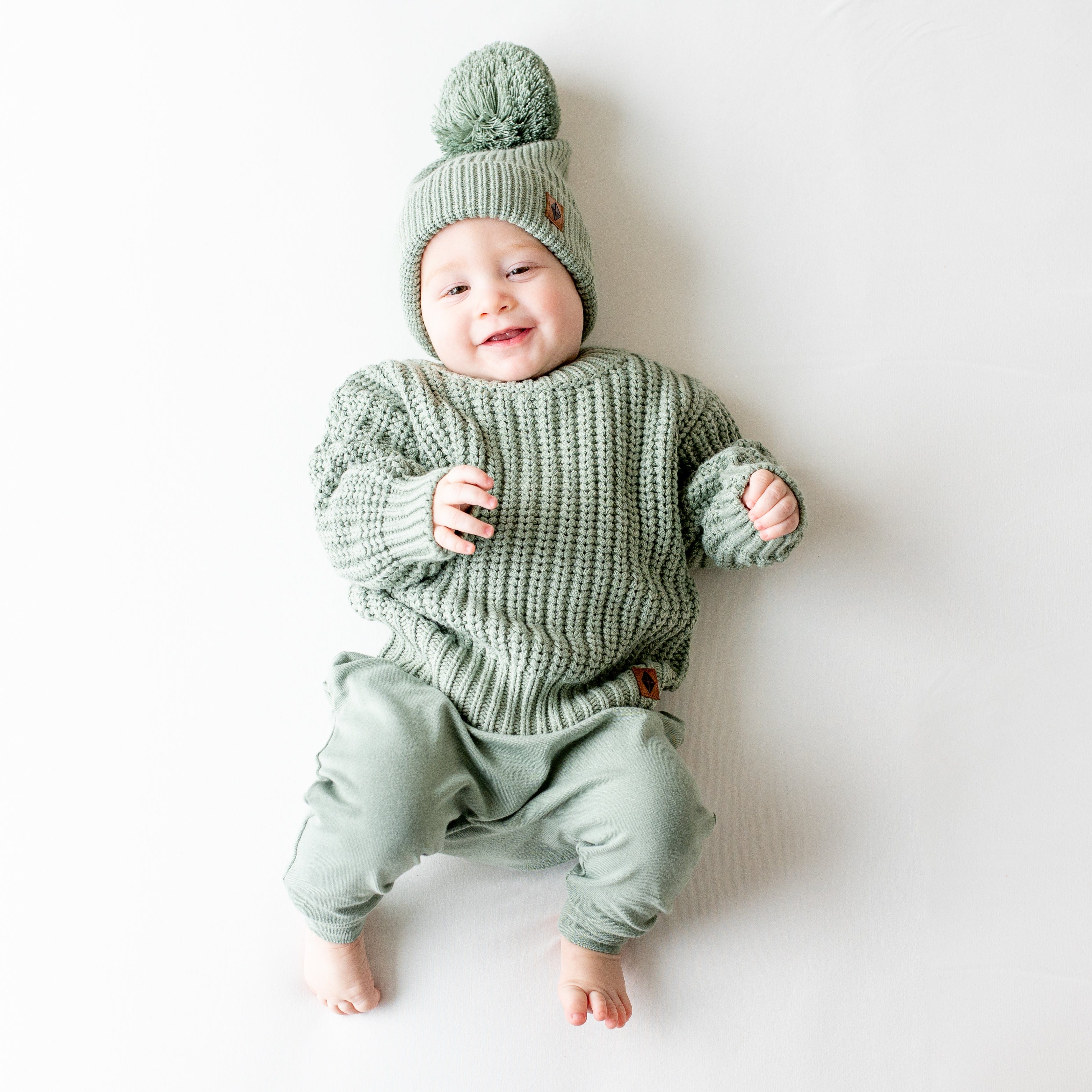 Infant wearing soft and stretchy Kyte Baby Chunky Knit Sweater in Thyme green