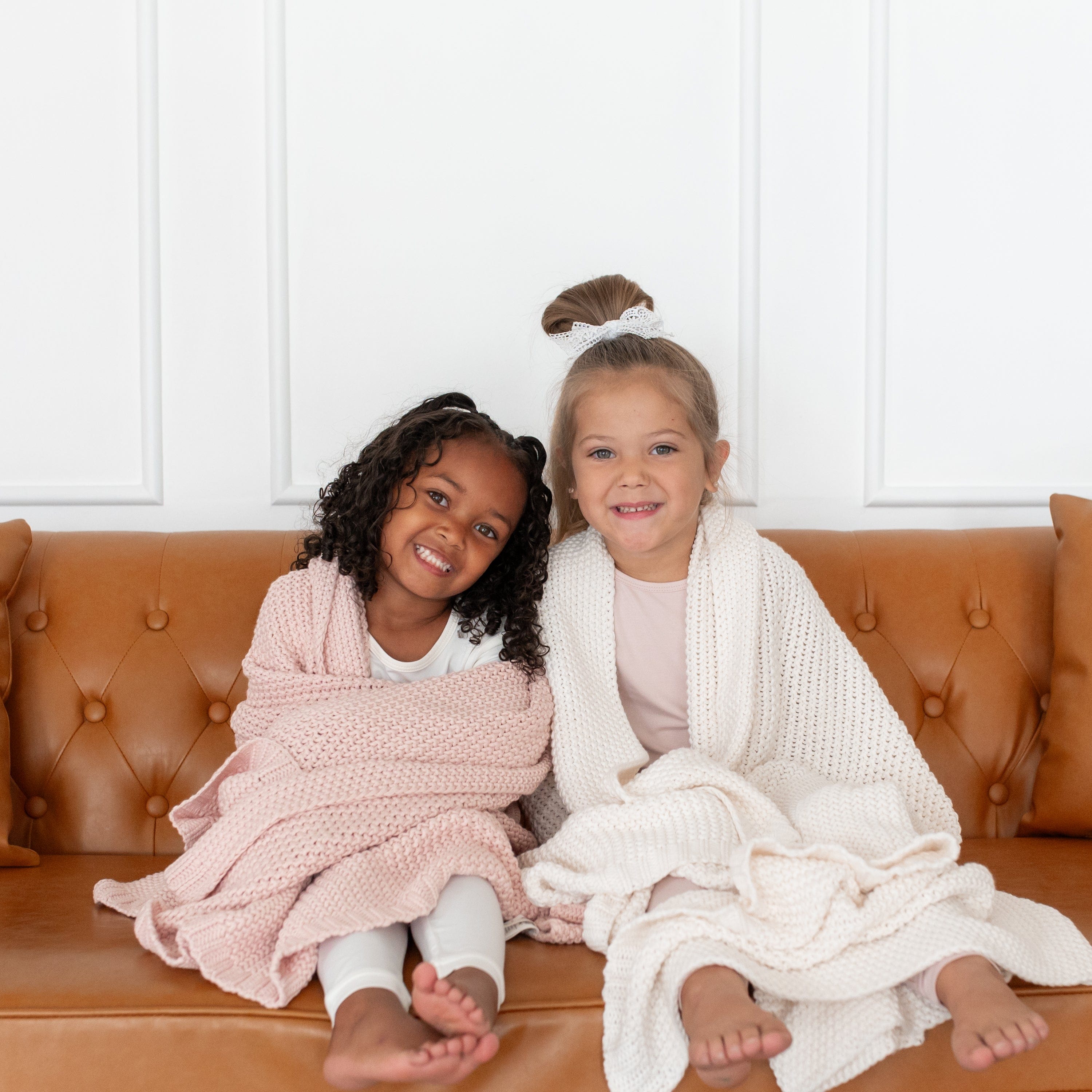 Girls snuggled under Kyte Baby Chunky Knit Toddler Blankets