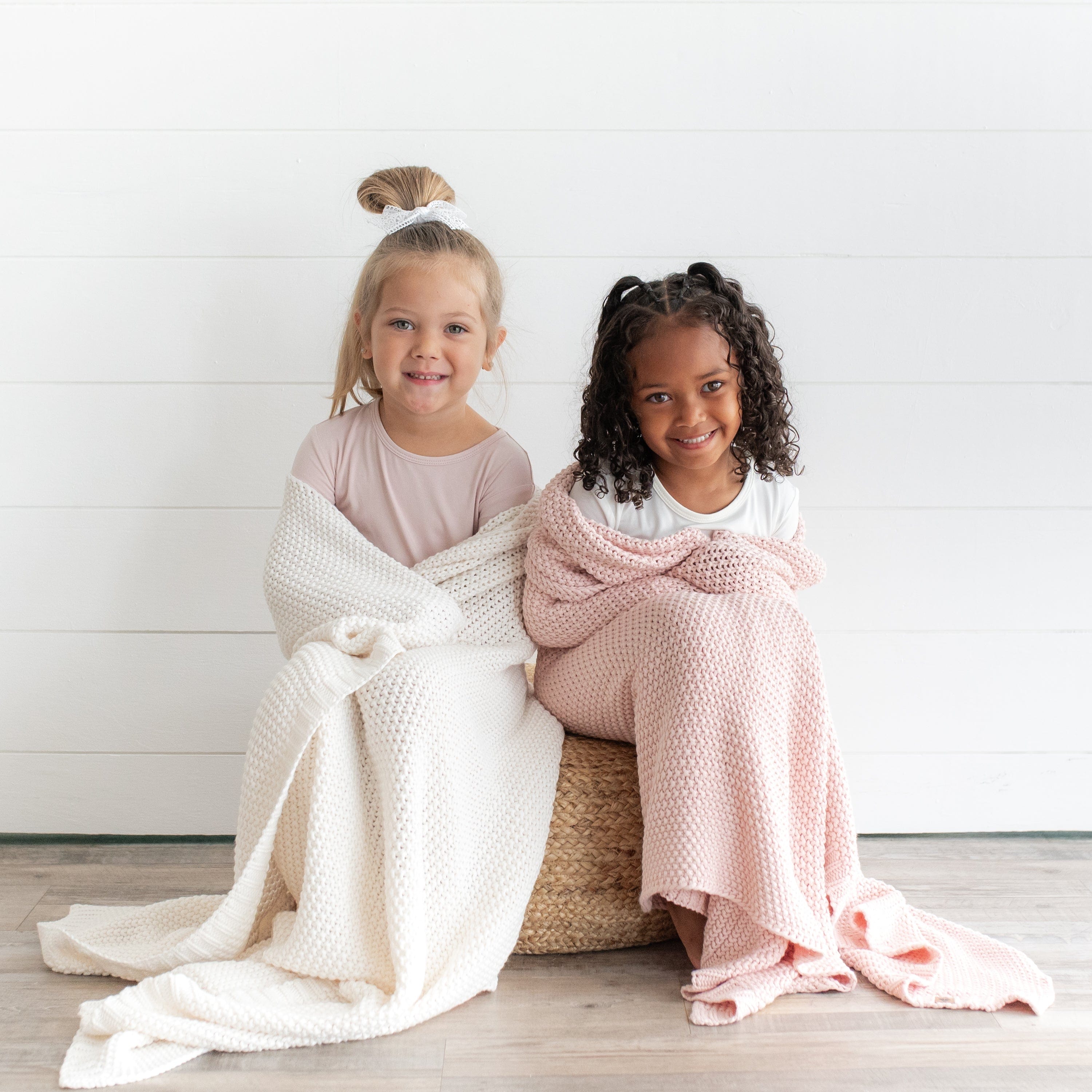Girls snuggled under Kyte Baby Chunky Knit Toddler Blankets