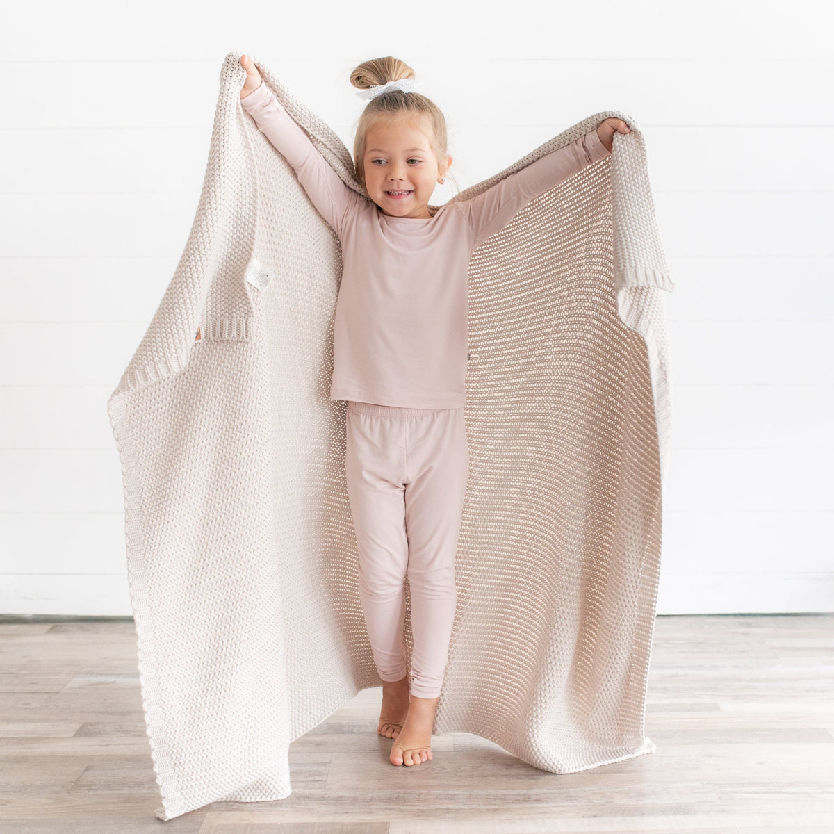 Girl using Kyte Baby Chunky Knit Toddler Blanket in Oat