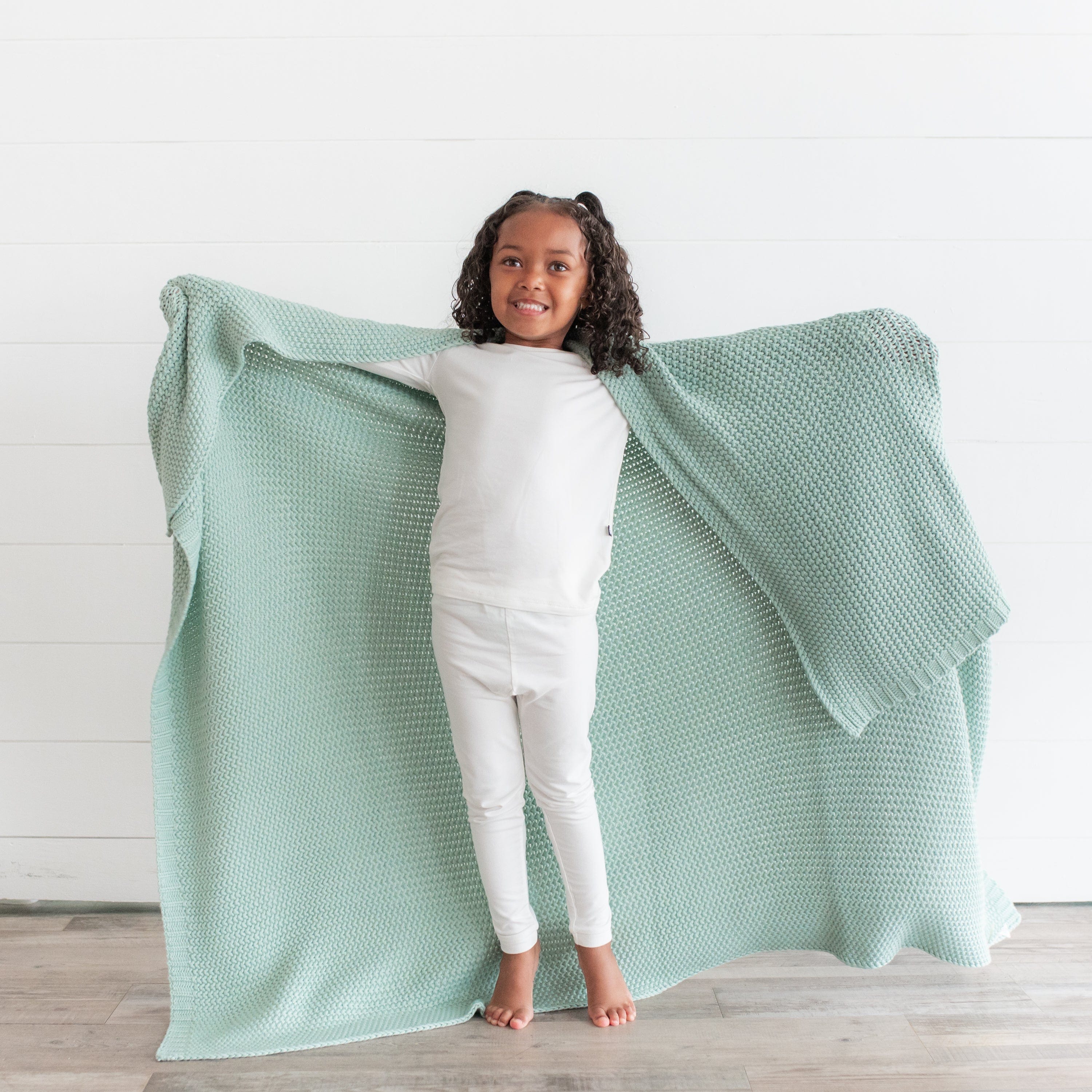 Girl using Kyte Baby Chunky Knit Toddler Blanket in Sage