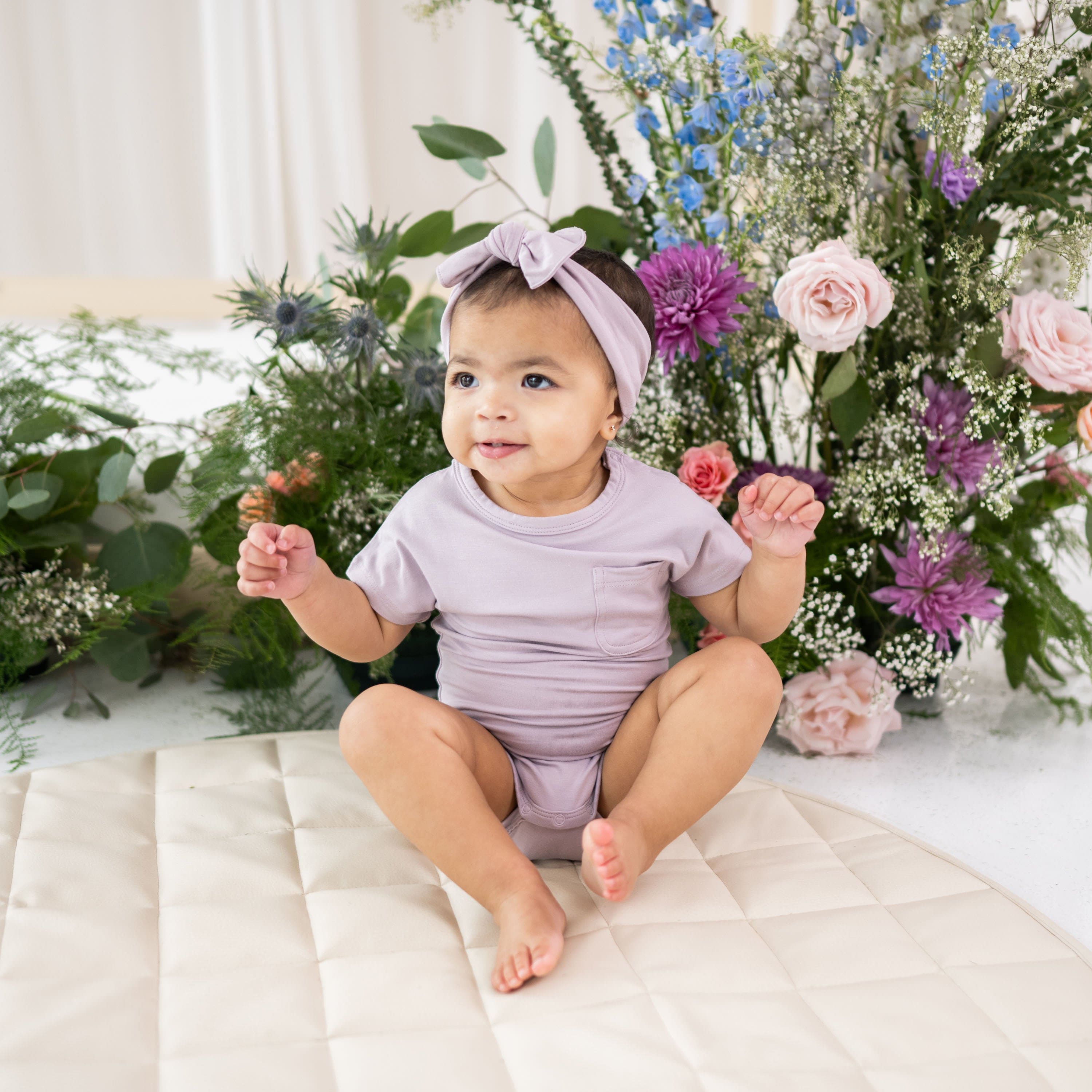 Infant wearing Kyte Baby Crew Neck Tee Bodysuit in Wisteria purple
