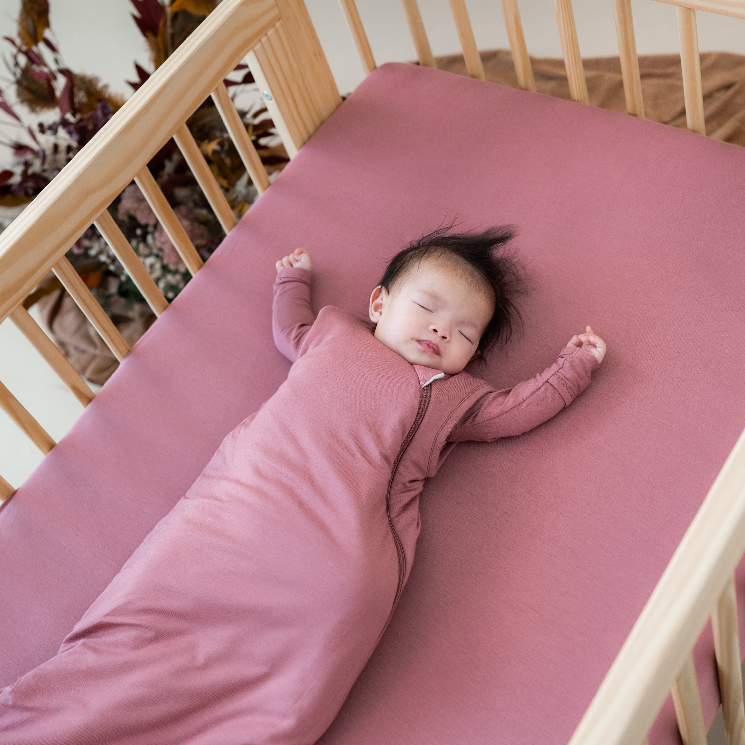 Infant sleeping on Kyte Baby standard Crib Sheet in Dusty Rose