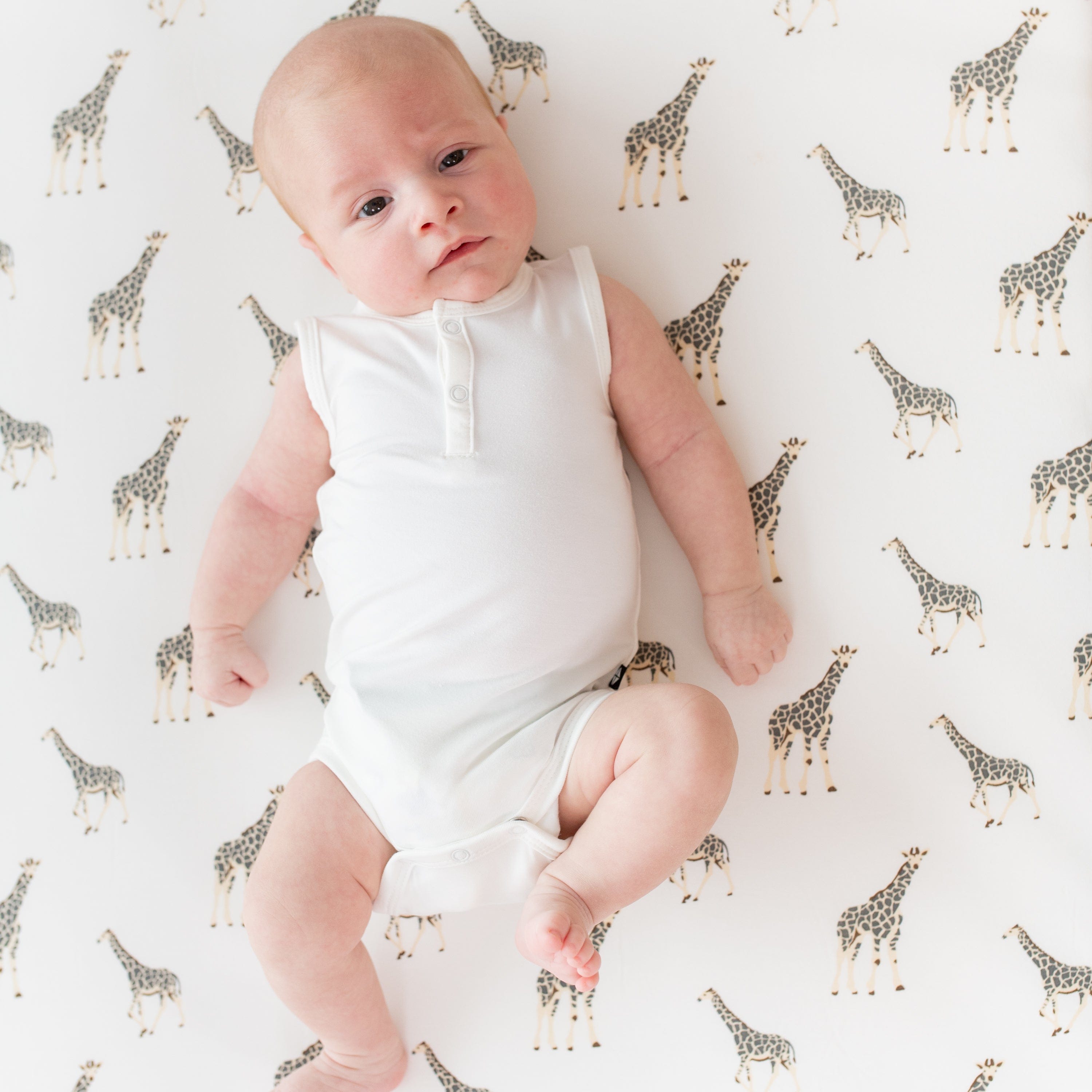 Infant laying on a Crib Sheet in Giraffe while wearing a Sleeveless Bodysuit in Cloud