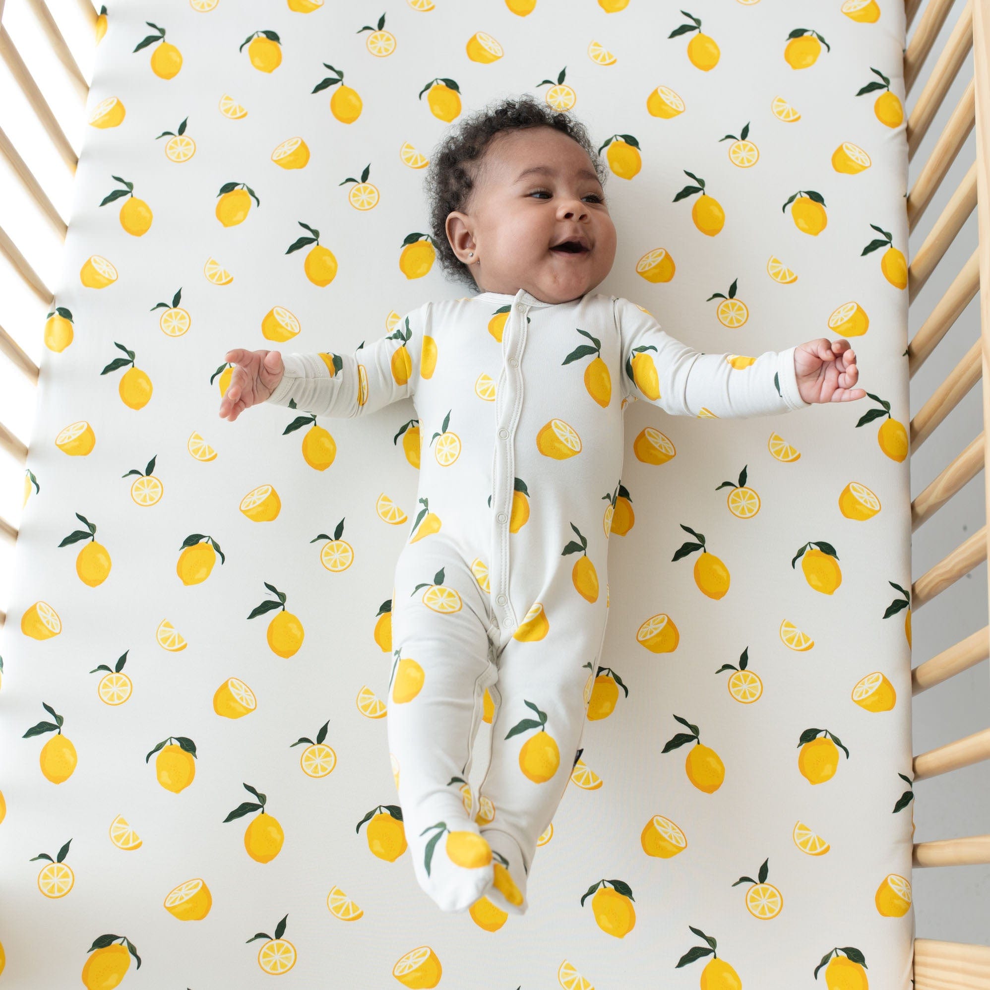 Infant laying on Kyte Baby Crib Sheet in Lemon