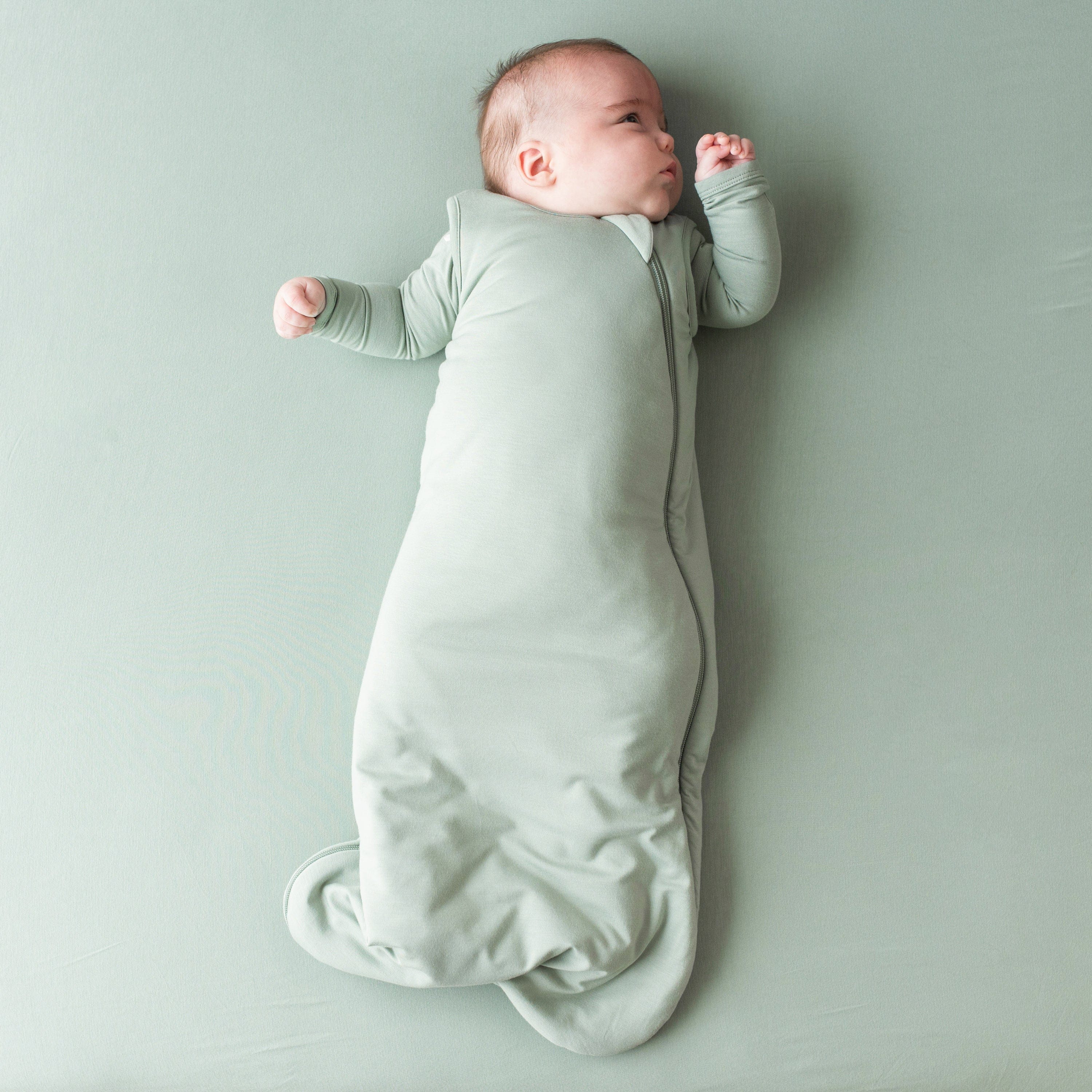 Infant wearing Kyte Baby bamboo TOG 2.5 Sleep Bag in Thyme Green