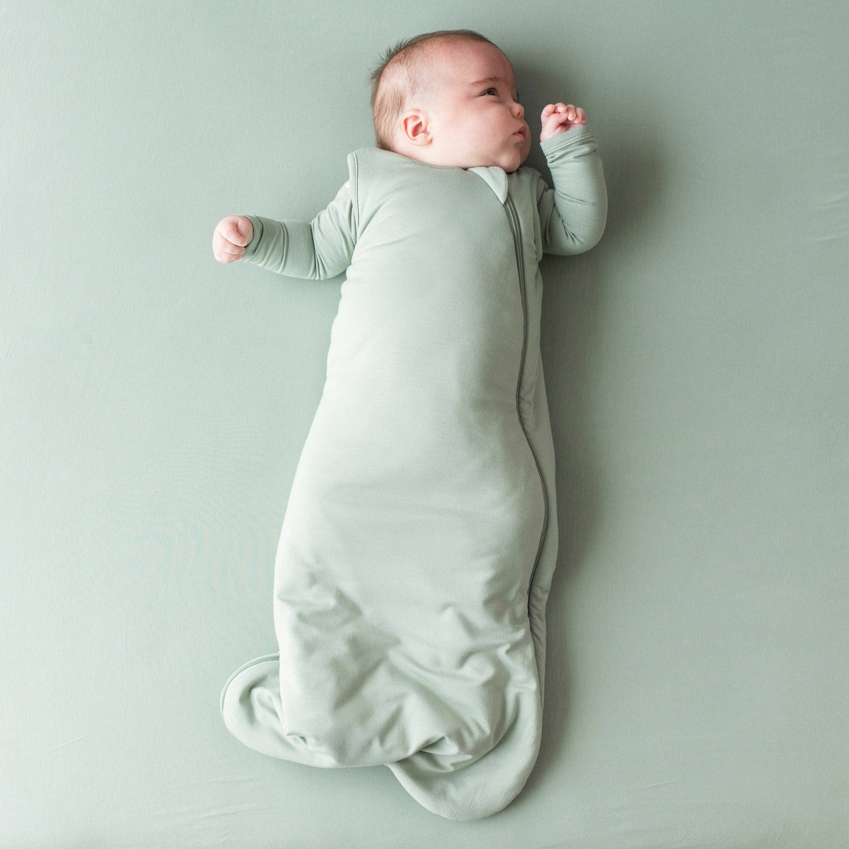 Infant wearing Kyte Baby bamboo TOG 2.5 Sleep Bag in Thyme Green