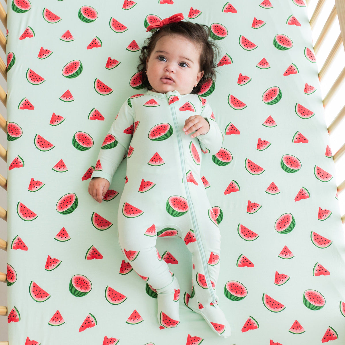 Infant laying on Kyte Baby Crib Sheet in Watermelon