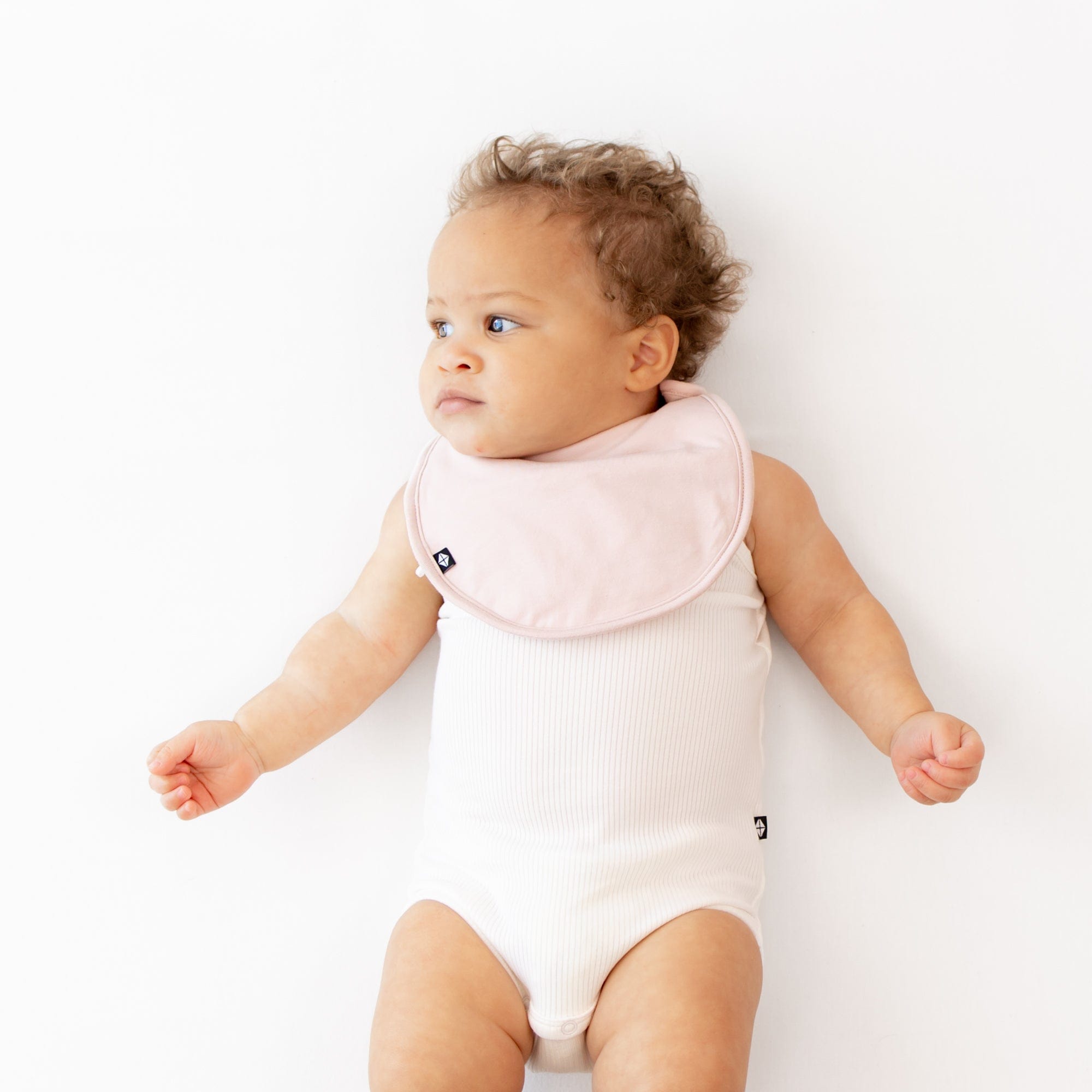 Infant wearing Kyte Baby Bamboo Cushy Bib in Blush pink