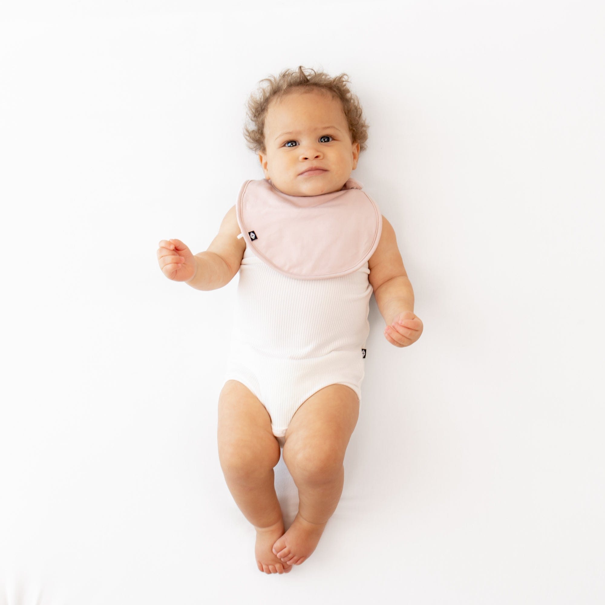 Infant wearing Kyte Baby Cushy Bib with adjustable snaps in Blush