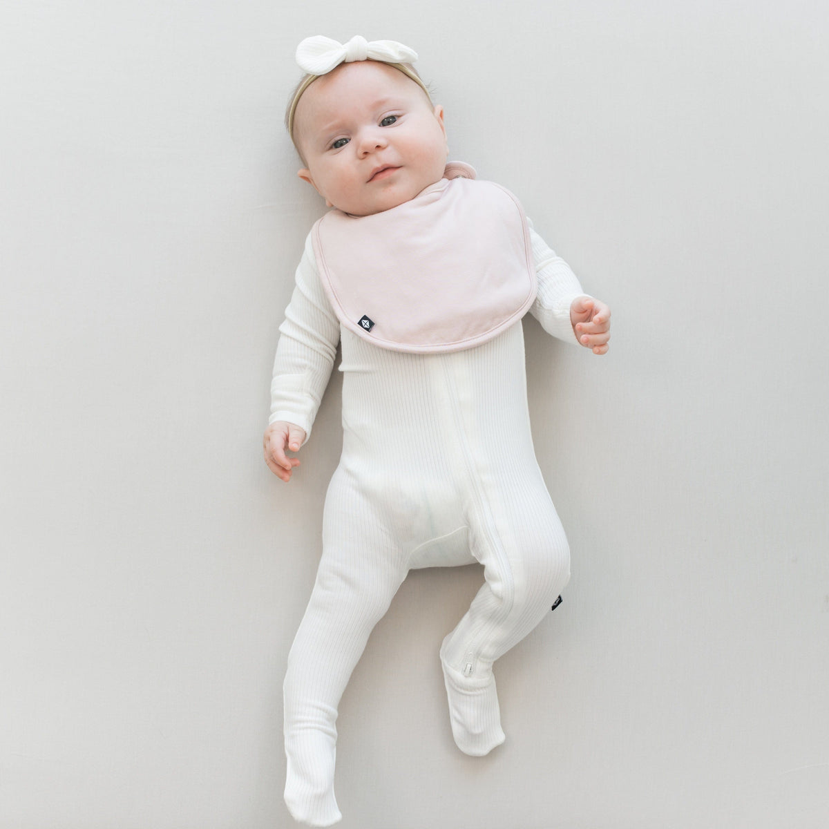 Infant wearing Kyte Baby Cushy Bib in Blush