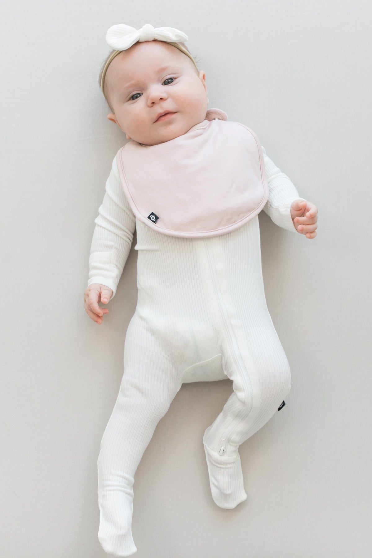 Infant wearing Kyte Baby Cushy Bib in Blush