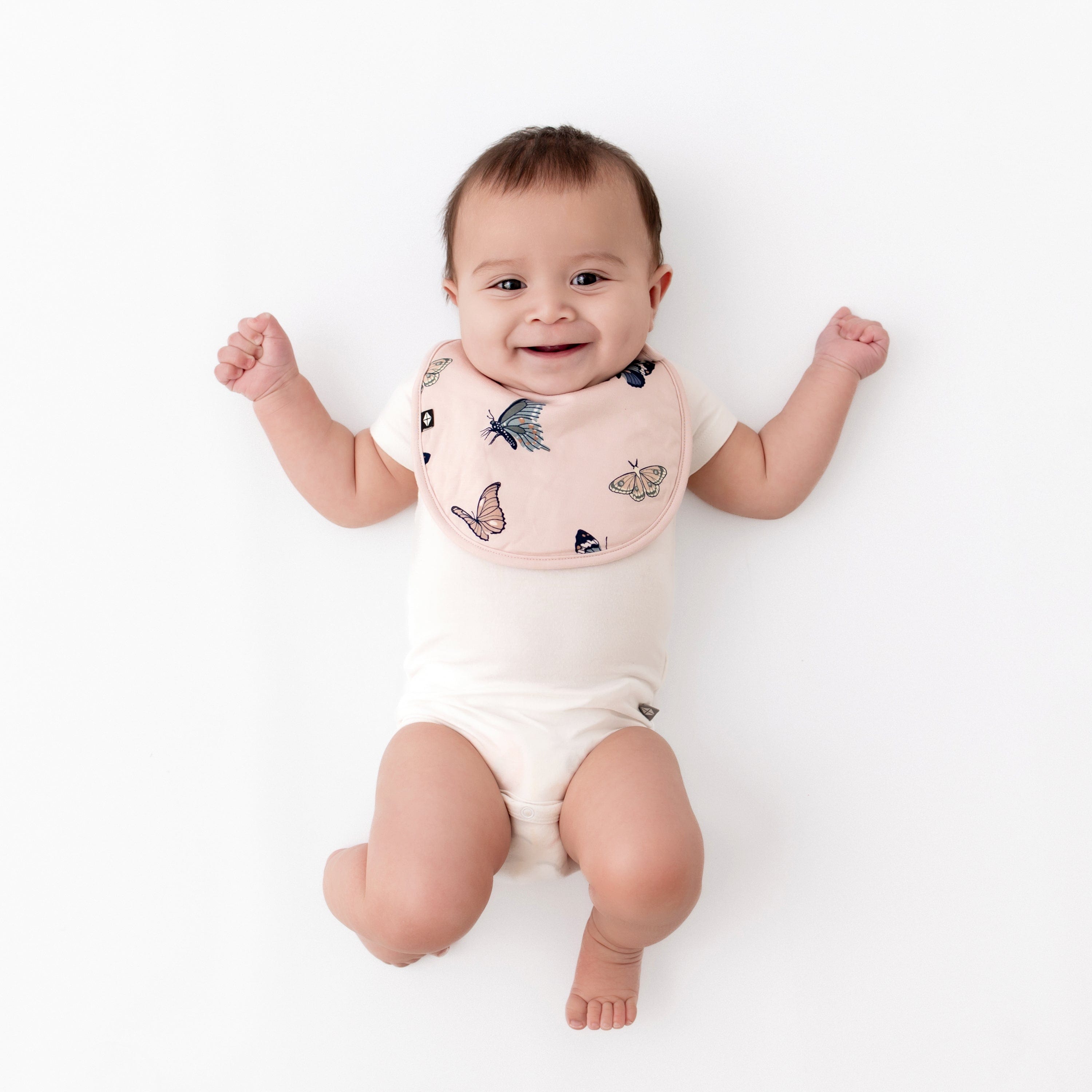 Infant wearing Kyte Baby Bamboo Cushy Bib in Blush Butterfly