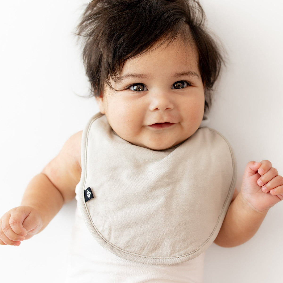 Infant wearing Kyte Baby Cushy Bib in Oat