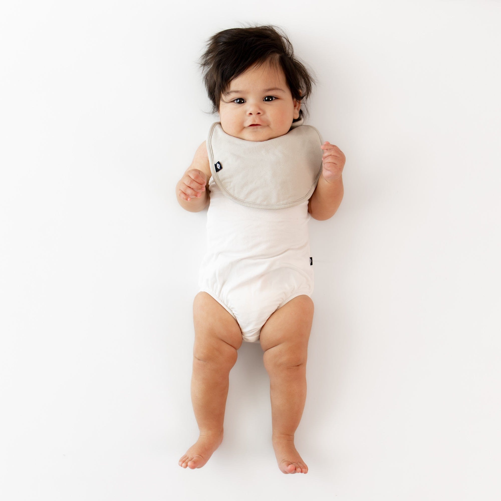 Infant wearing Kyte Baby Cushy Bamboo Bib in Oat