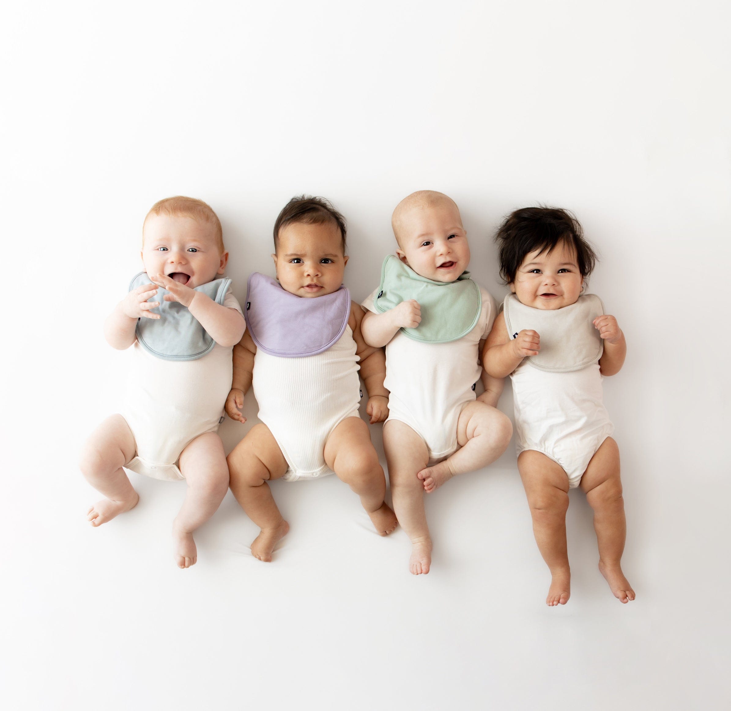 Babies wearing Kyte Baby Cushy Bib in core colors