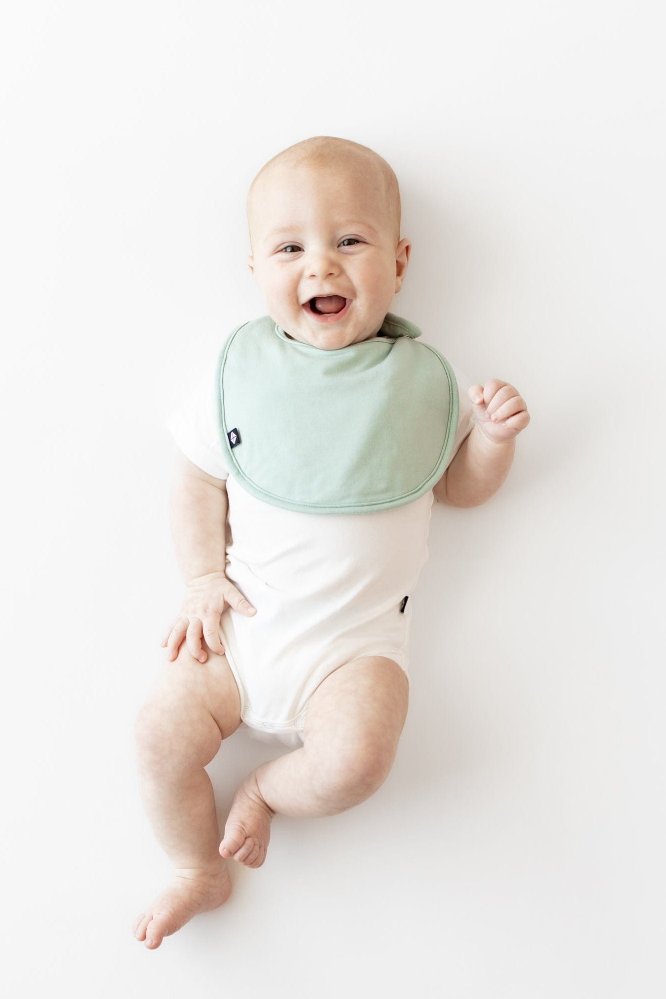 Infant wearing Kyte Baby Cushy Bib in Sage