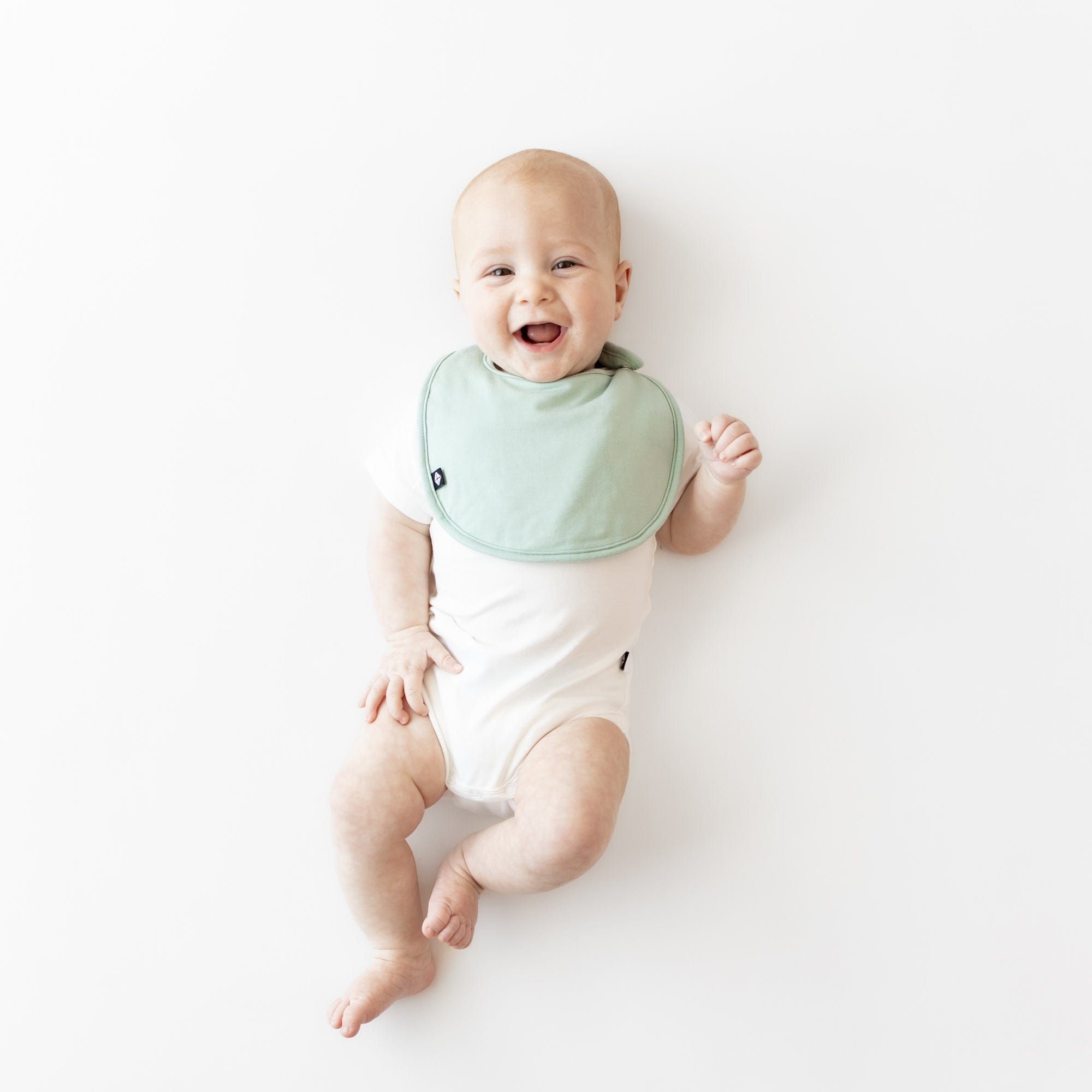 Infant wearing Kyte Baby Cushy Bib in Sage