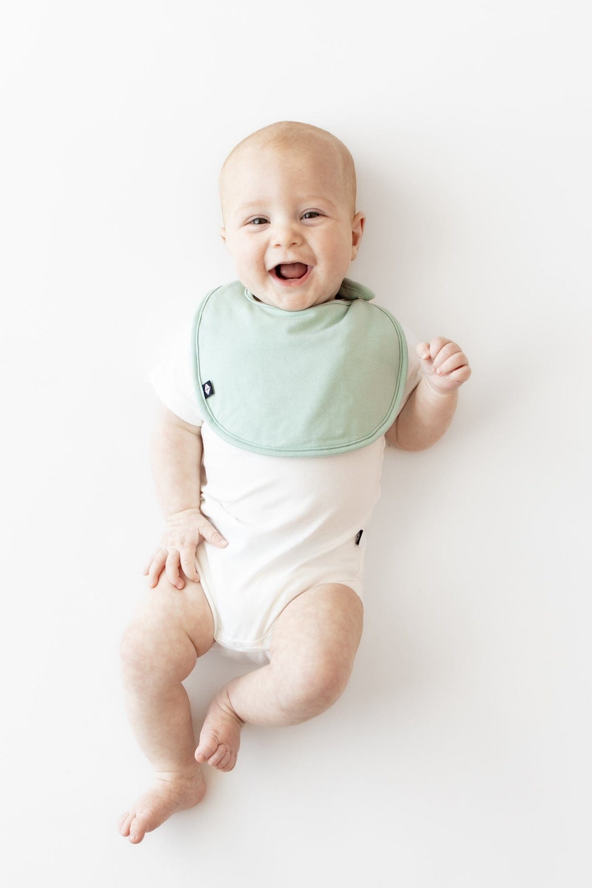 Infant wearing Kyte Baby Cushy Bib in Sage