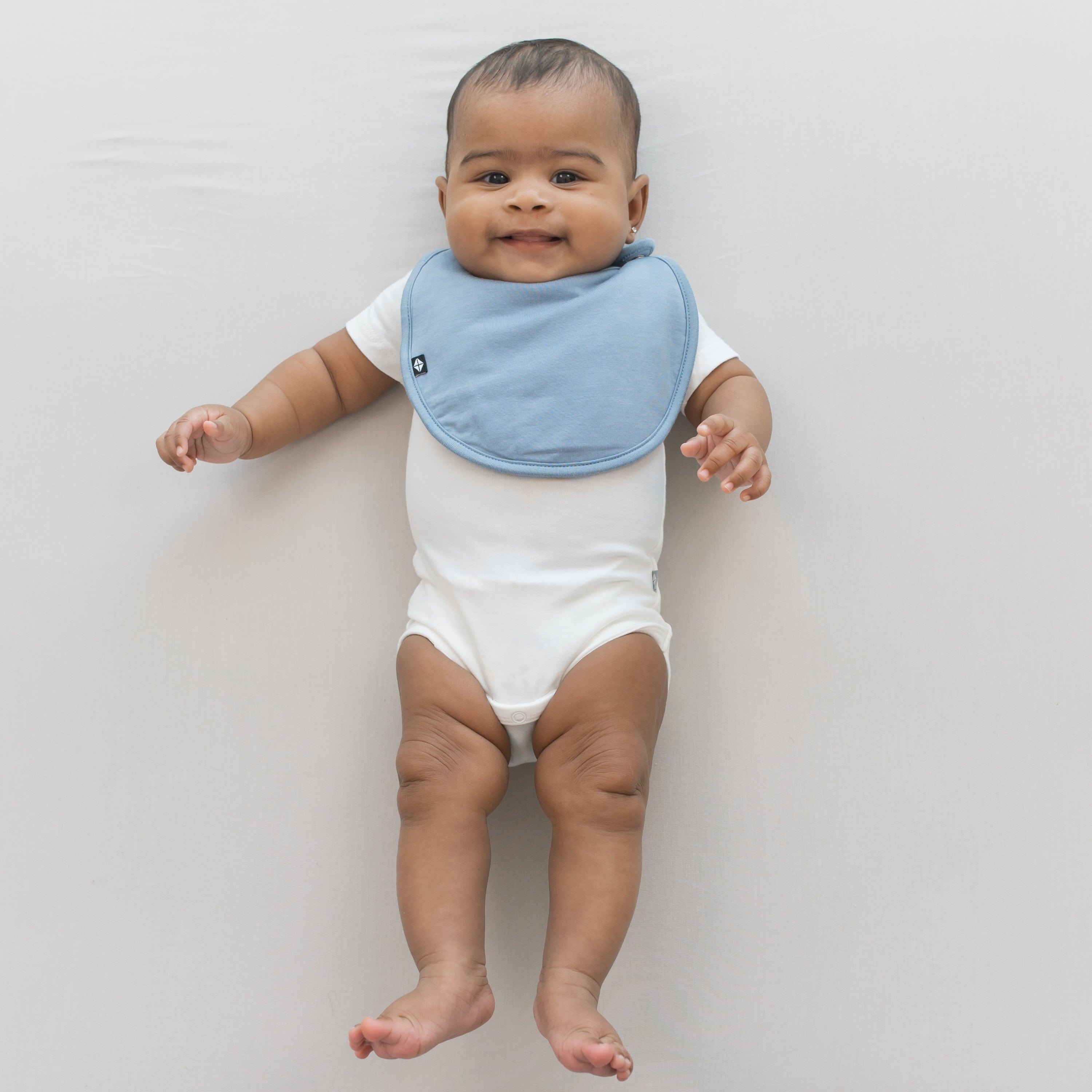 Infant wearing Kyte Baby Cushy Bamboo Bib in Slate blue