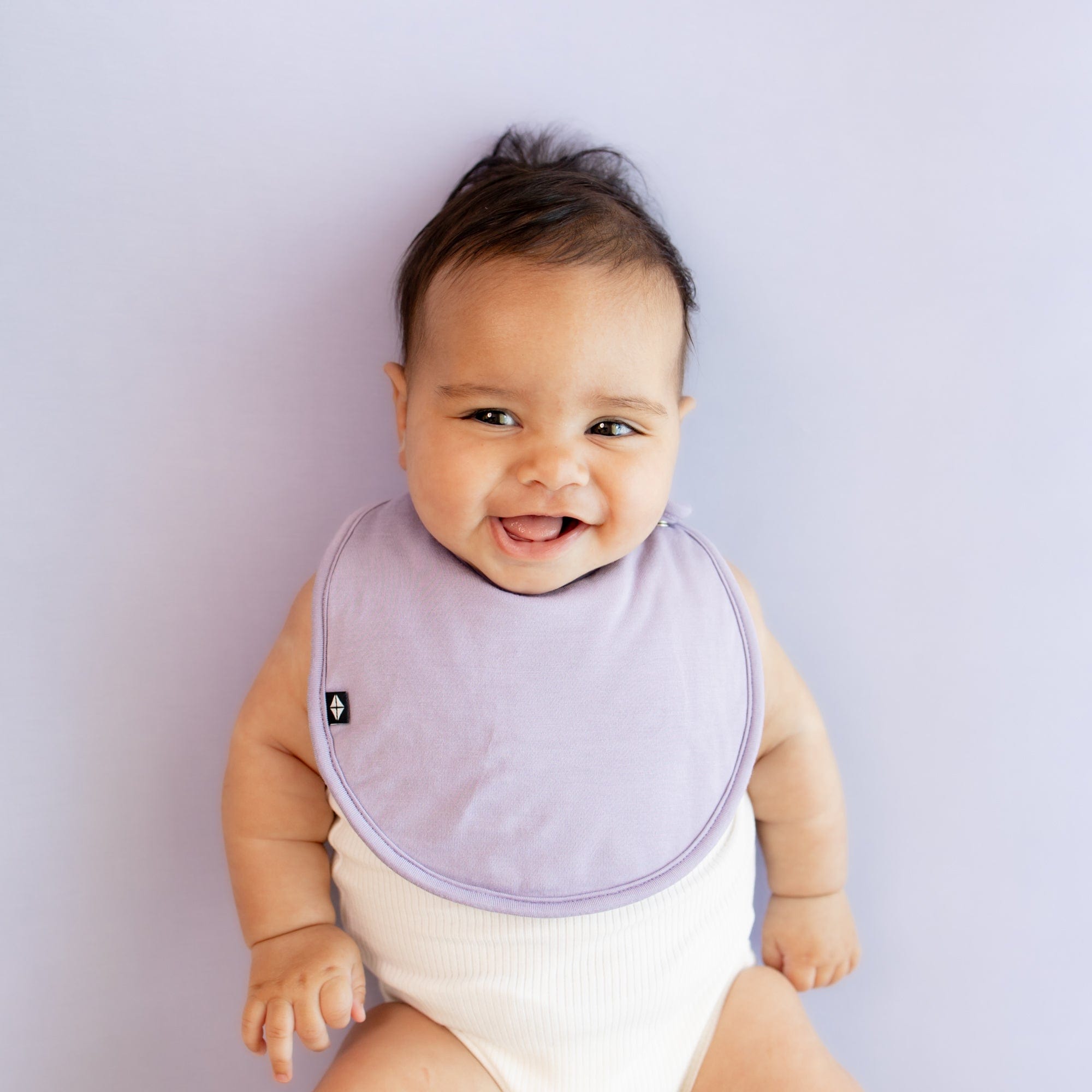 Infant wearing Kyte Baby Cushy Bamboo Bib in Taro