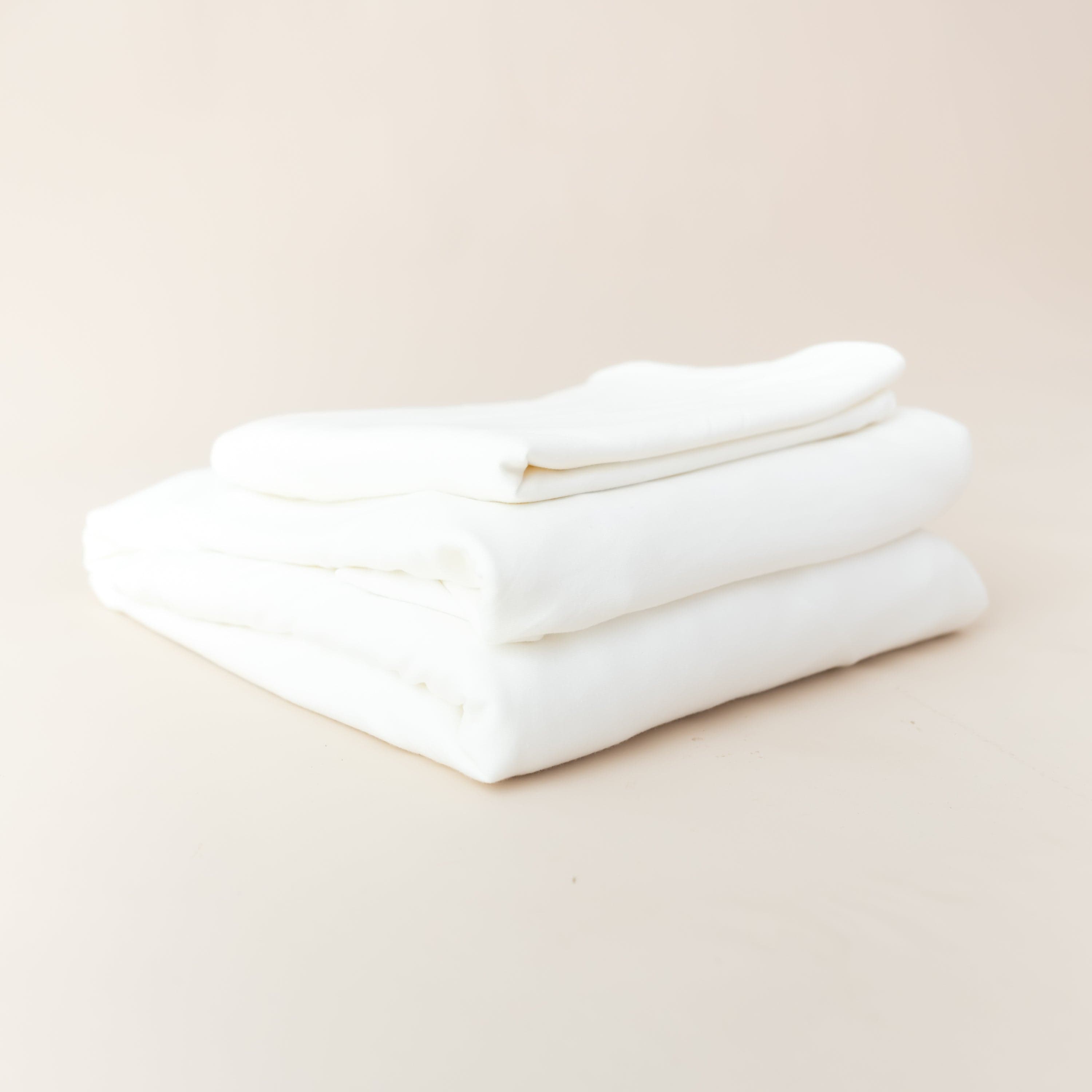 Folded Stack of Kyte Baby Fitted Sheet with Pillowcases in Cloud White