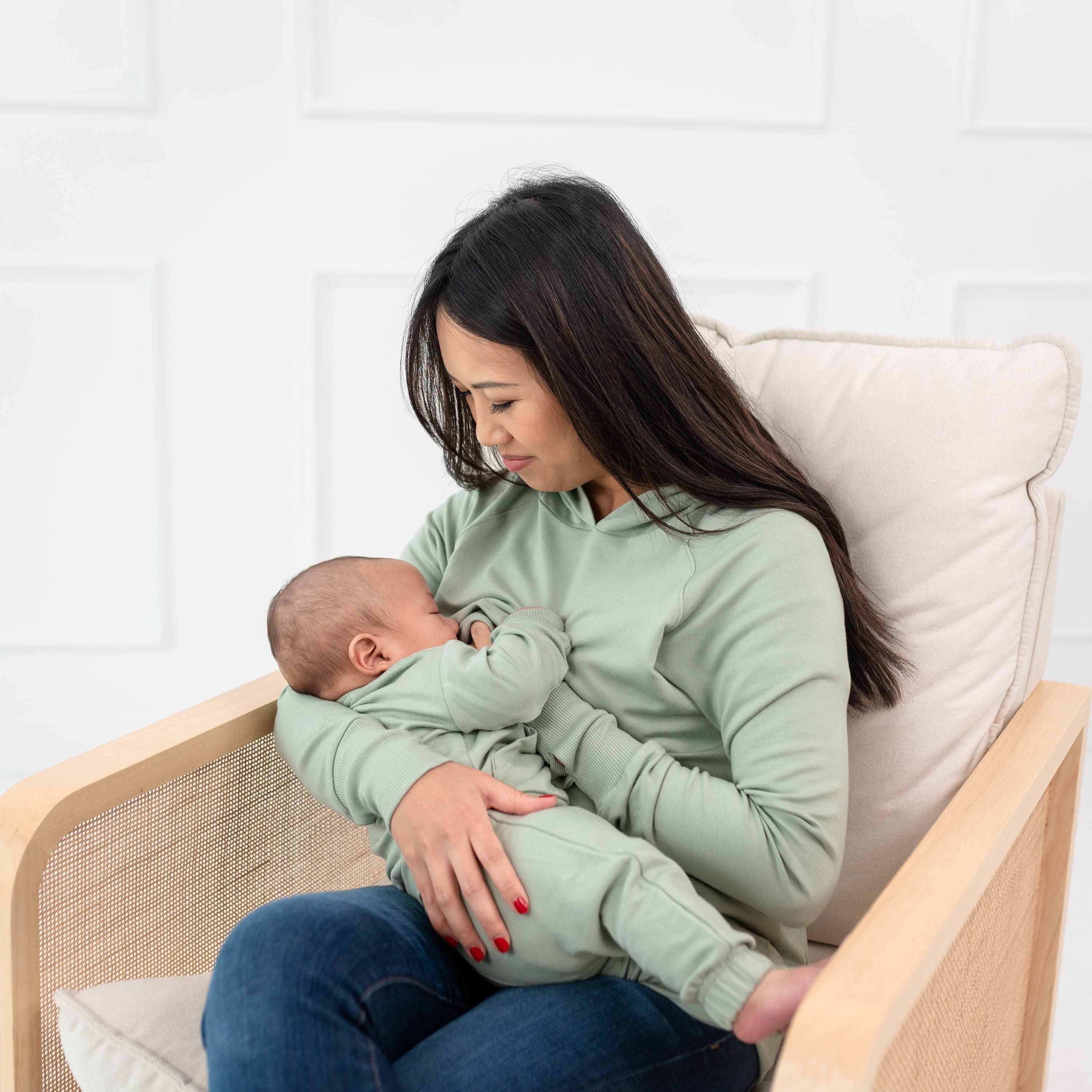 Mom nursing infant while wearing Kyte Baby Women's French Terry Nursing Hoodie in Thyme