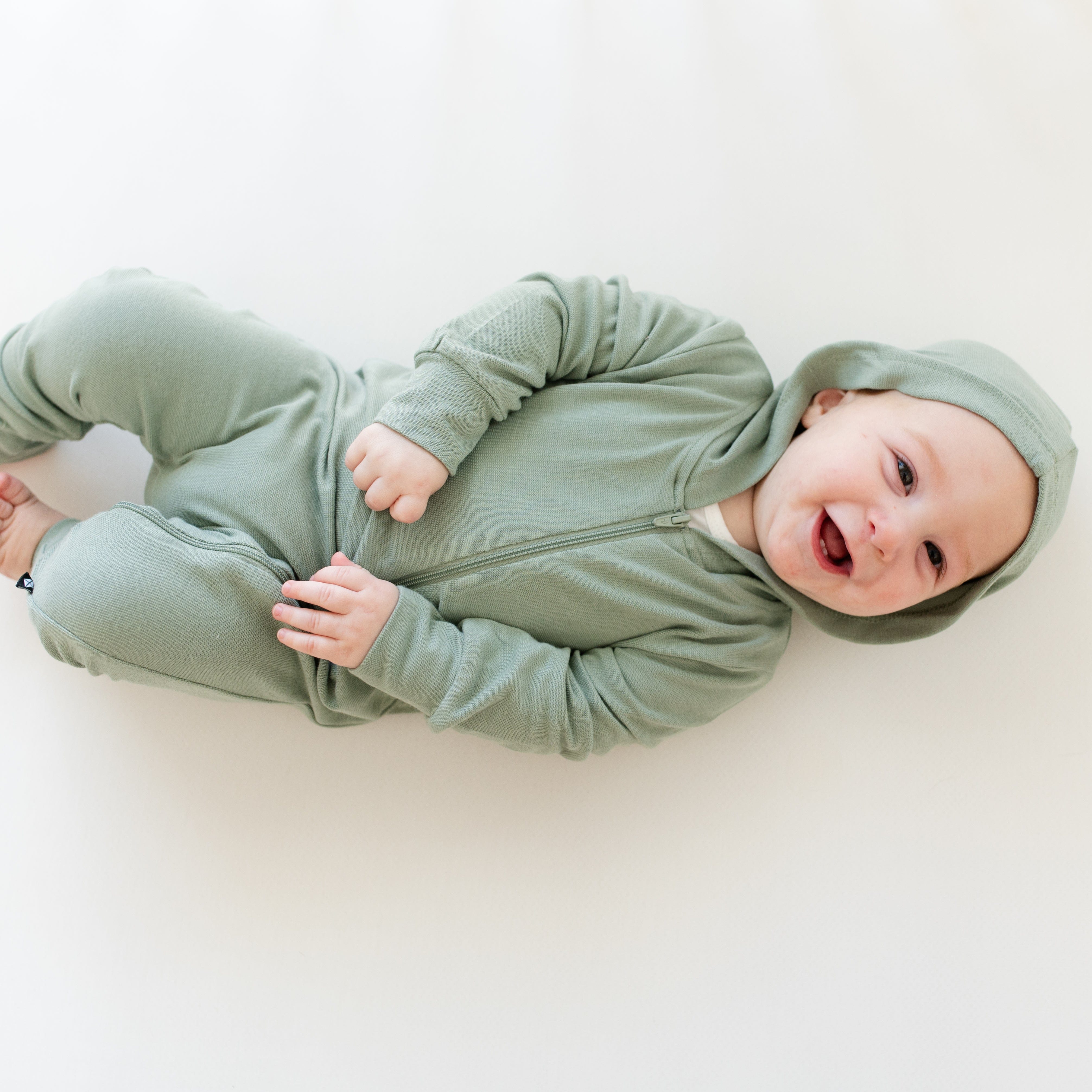 Infant wearing Kyte Baby Bamboo Jersey Hooded Zippered Romper in Thyme