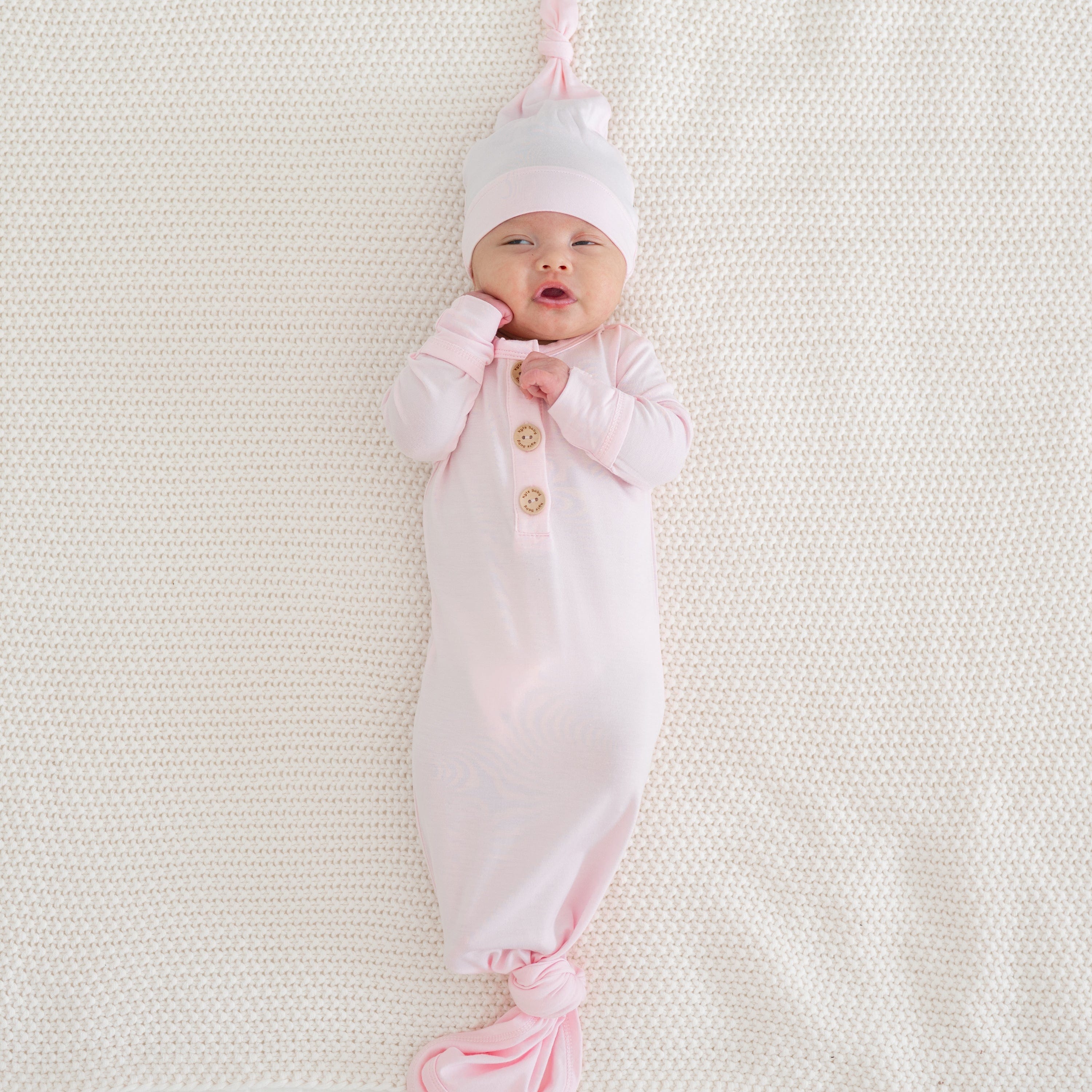 Newborn wearing Kyte Baby Knotted Gown with Hat Set in Sakura pink