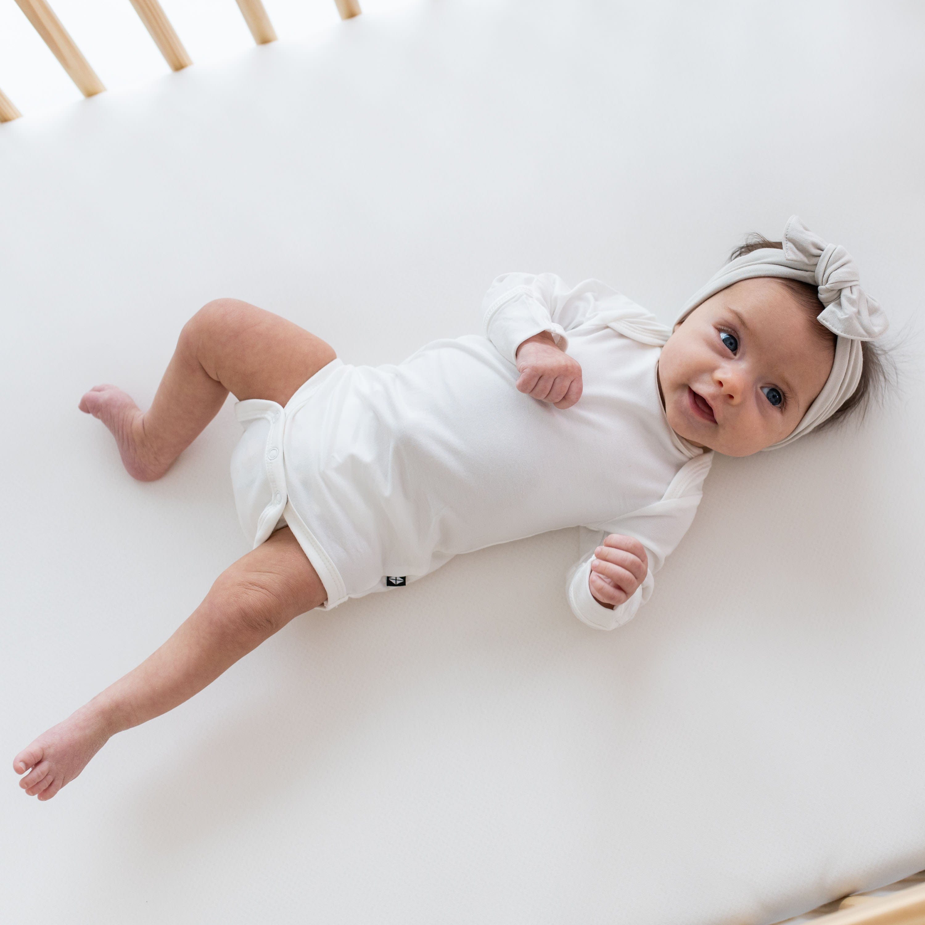 Baby wearing Kyte Baby Long Sleeve infant Bodysuit in Cloud