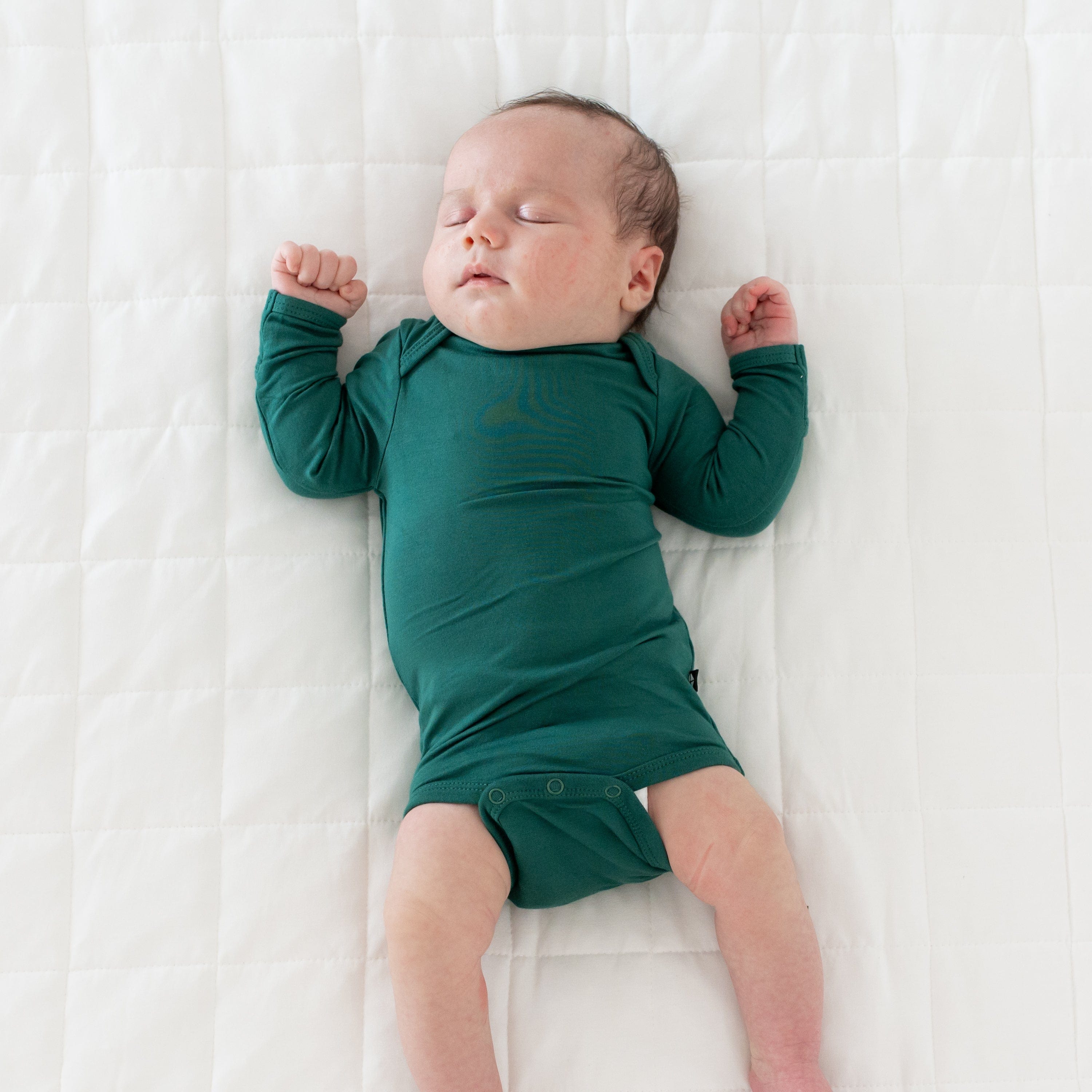 Sleeping baby wearing Kyte Baby Long Sleeve Bodysuit in Emerald